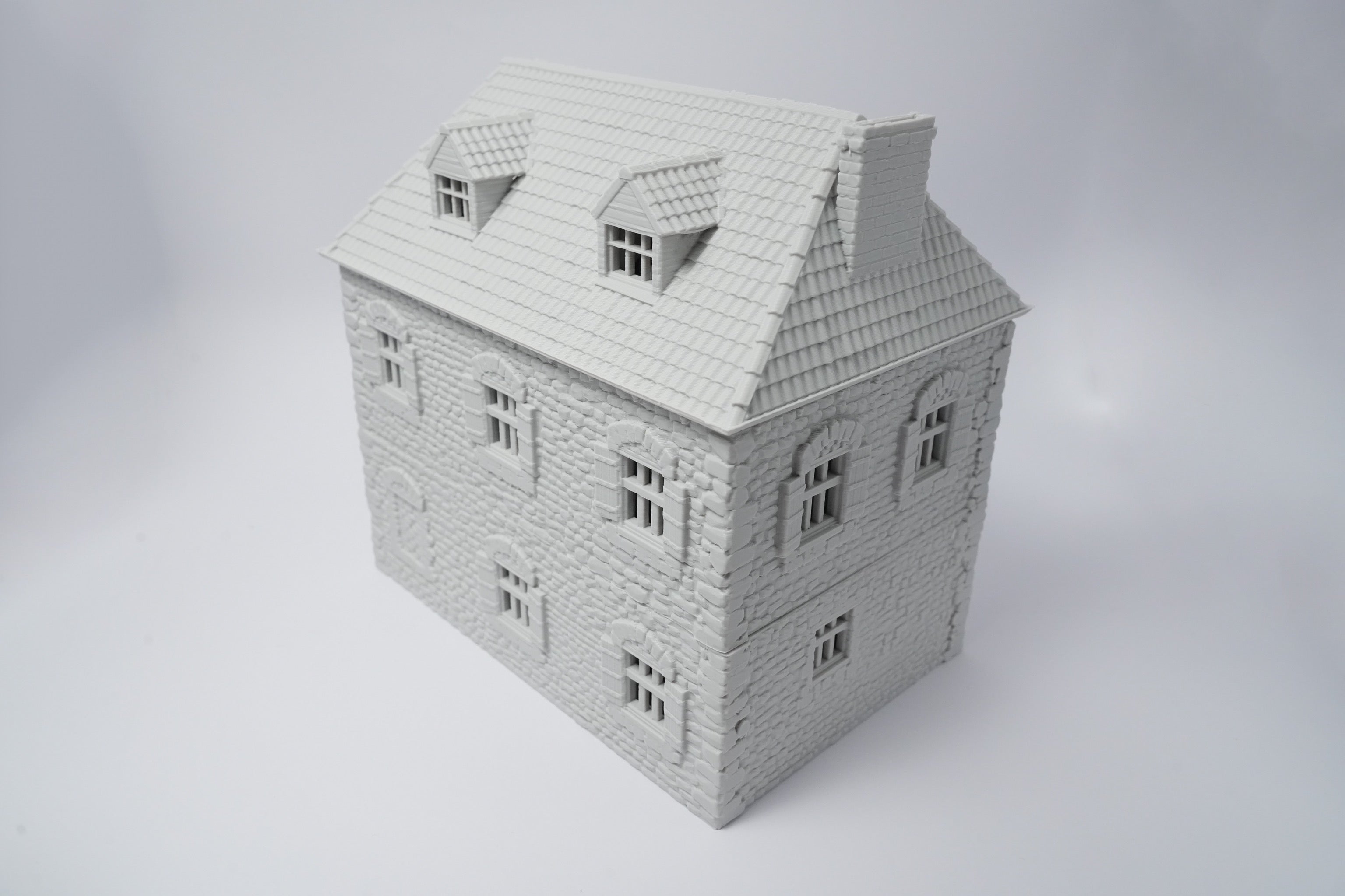 Graues Miniaturhaus im französischen Bauernhausstil mit Dachgauben und detaillierten Fensterrahmen.