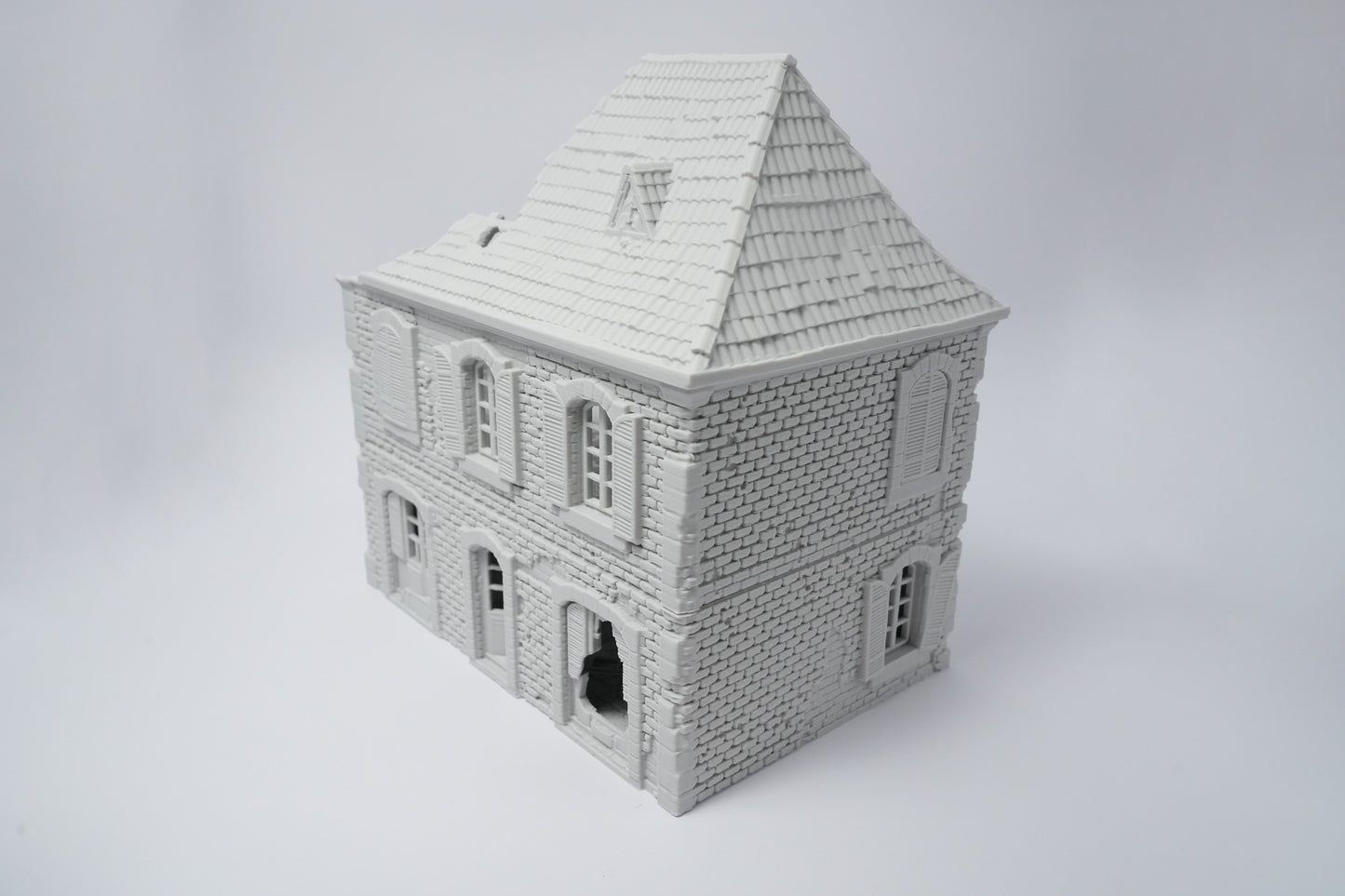 Graues, detailliertes Miniaturhaus mit zerfallener Fassade und Schieferdach, 28 mm Maßstab.