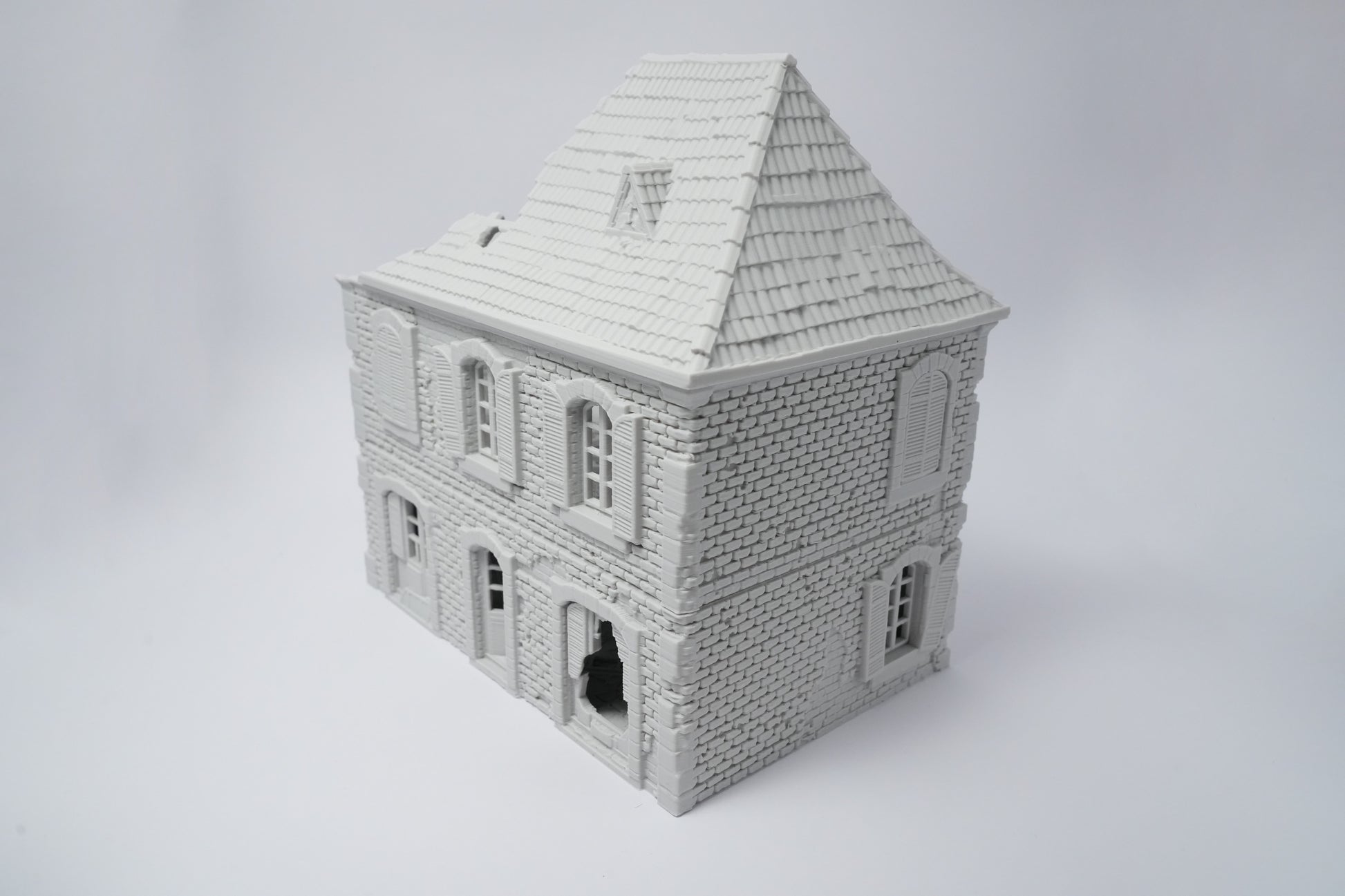 Graues, detailliertes Miniaturhaus mit zerfallener Fassade und Schieferdach, 28 mm Maßstab.