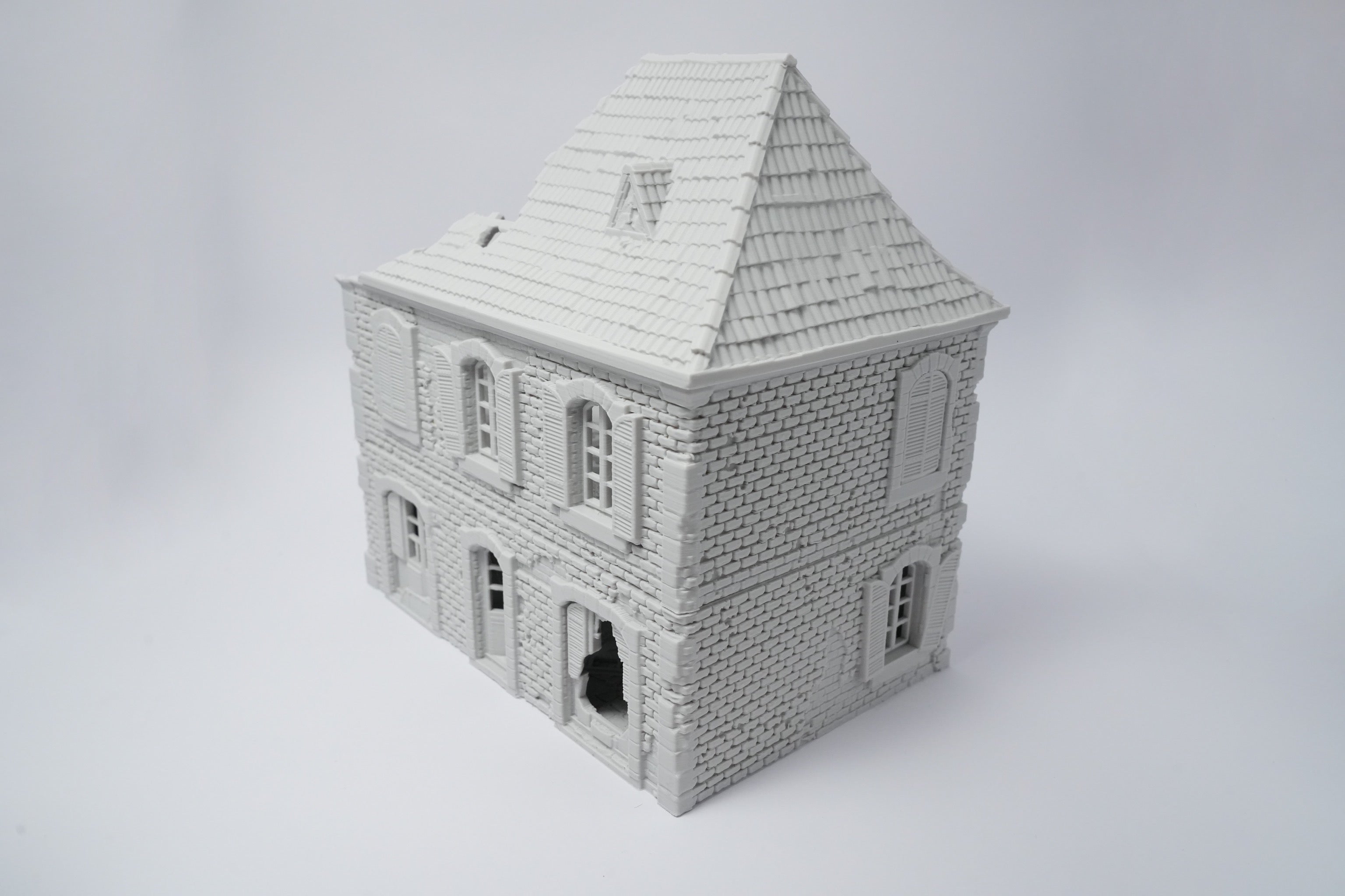 Graues, detailliertes Miniaturhaus mit zerfallener Fassade und Schieferdach, 28 mm Maßstab.