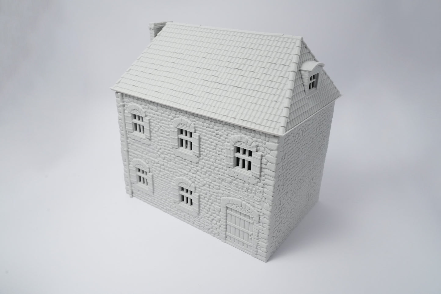Weißes Modell eines französischen Bauernhauses mit Schindel-Dach und symmetrischen Fenstern.