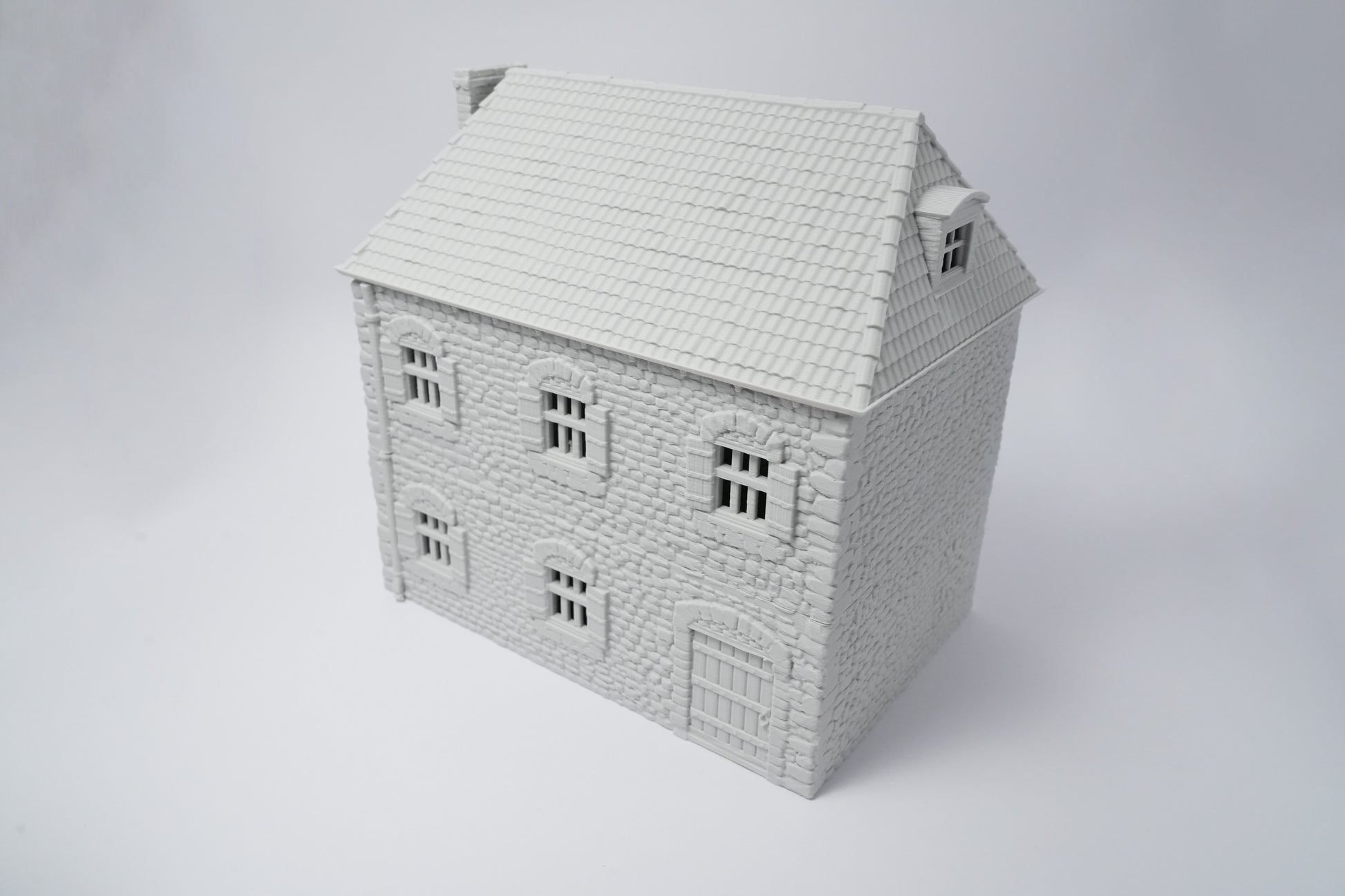 Weißes Modell eines französischen Bauernhauses mit Schindel-Dach und symmetrischen Fenstern.