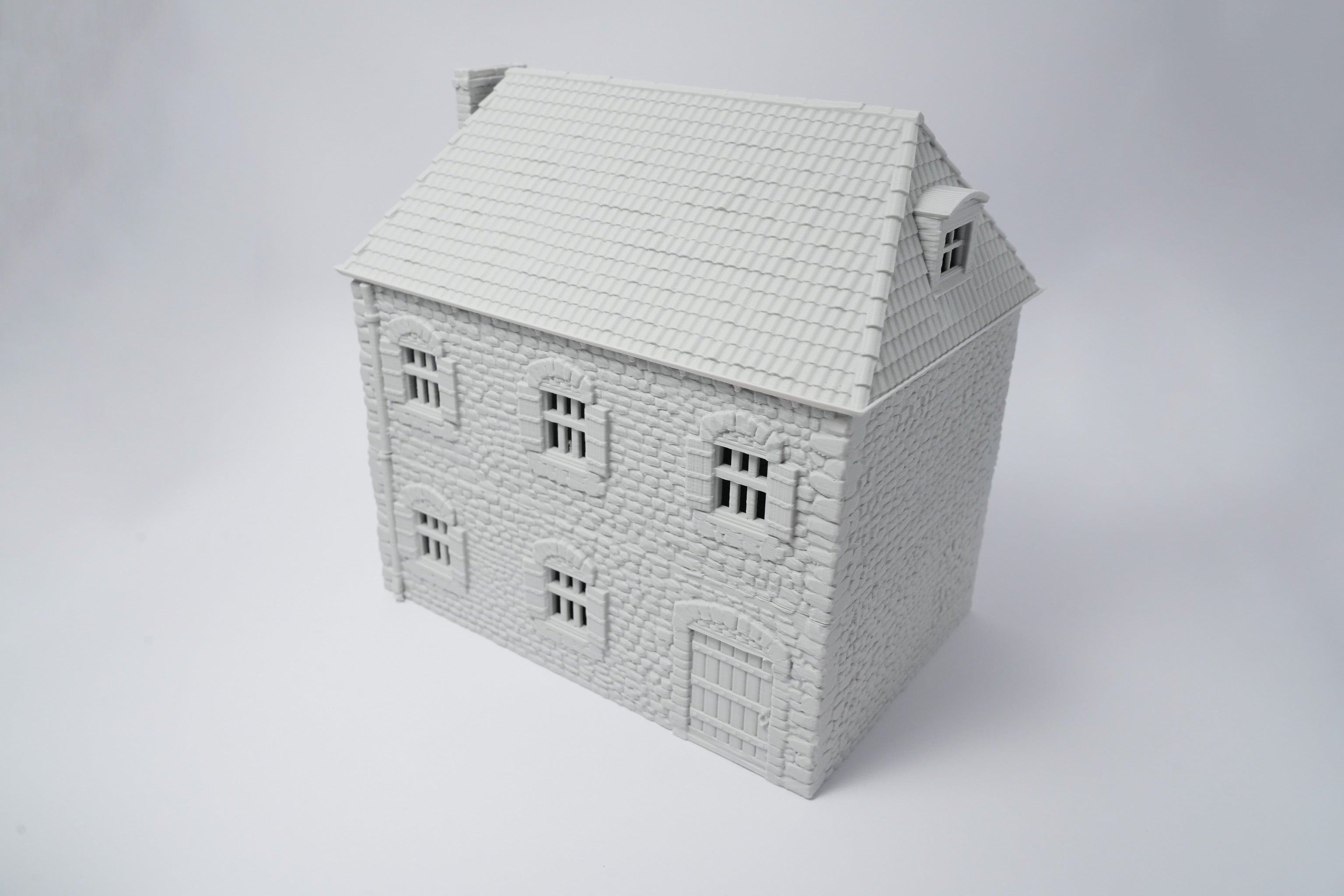 Weißes Modell eines französischen Bauernhauses mit Schindel-Dach und symmetrischen Fenstern.