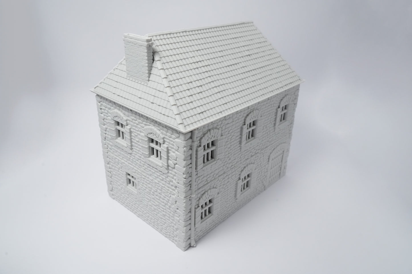 Grau gestrichenes französisches Bauernhaus mit schrägem Dach und kleinen Fenstern, Modellbau.