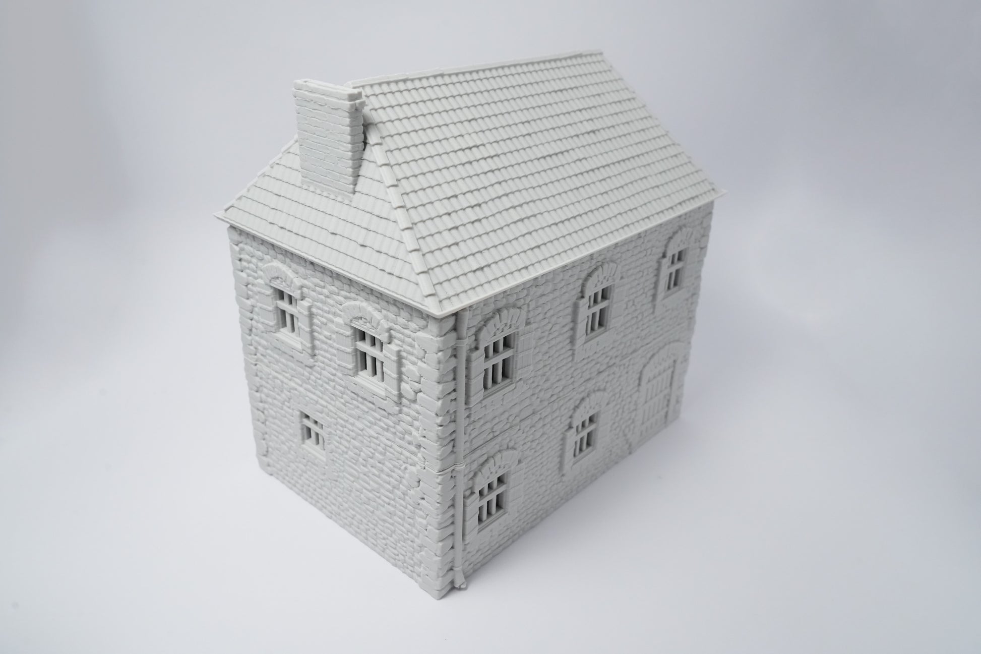 Grau gestrichenes französisches Bauernhaus mit schrägem Dach und kleinen Fenstern, Modellbau.