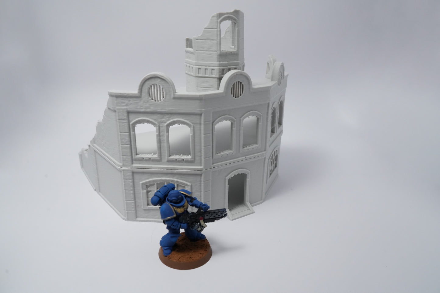 Graue zerfallene Backsteinruine mit zerstörten Fenstern und Ecken, daneben Miniatur-Soldat in Blau.