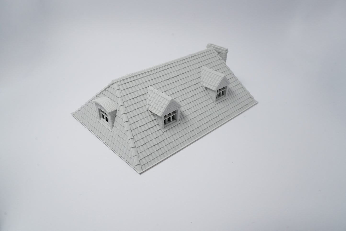Grau unbemaltes Modell eines französischen Farmhauses mit schrägem Dach und zwei Dachgauben.