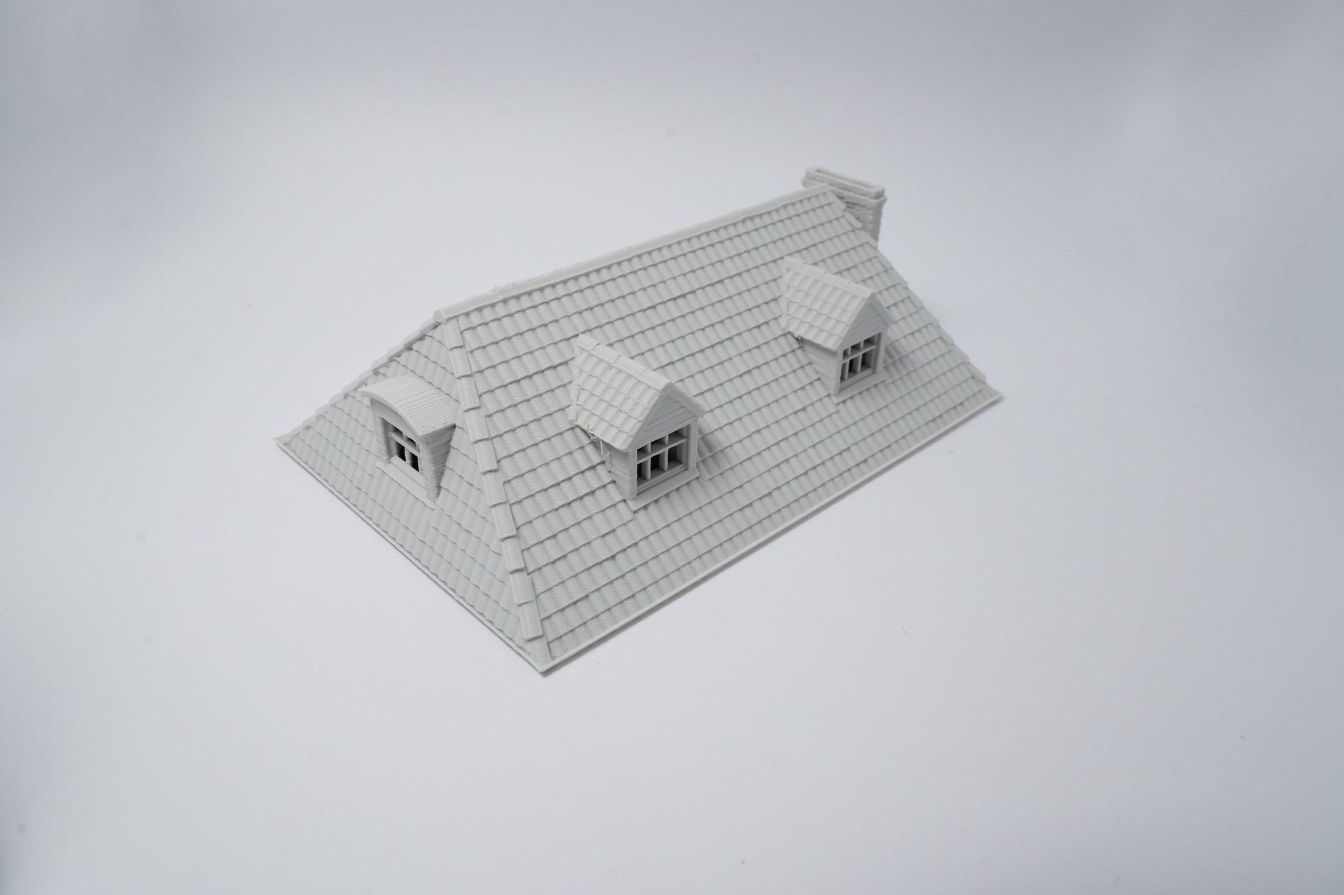 Grau unbemaltes Modell eines französischen Farmhauses mit schrägem Dach und zwei Dachgauben.