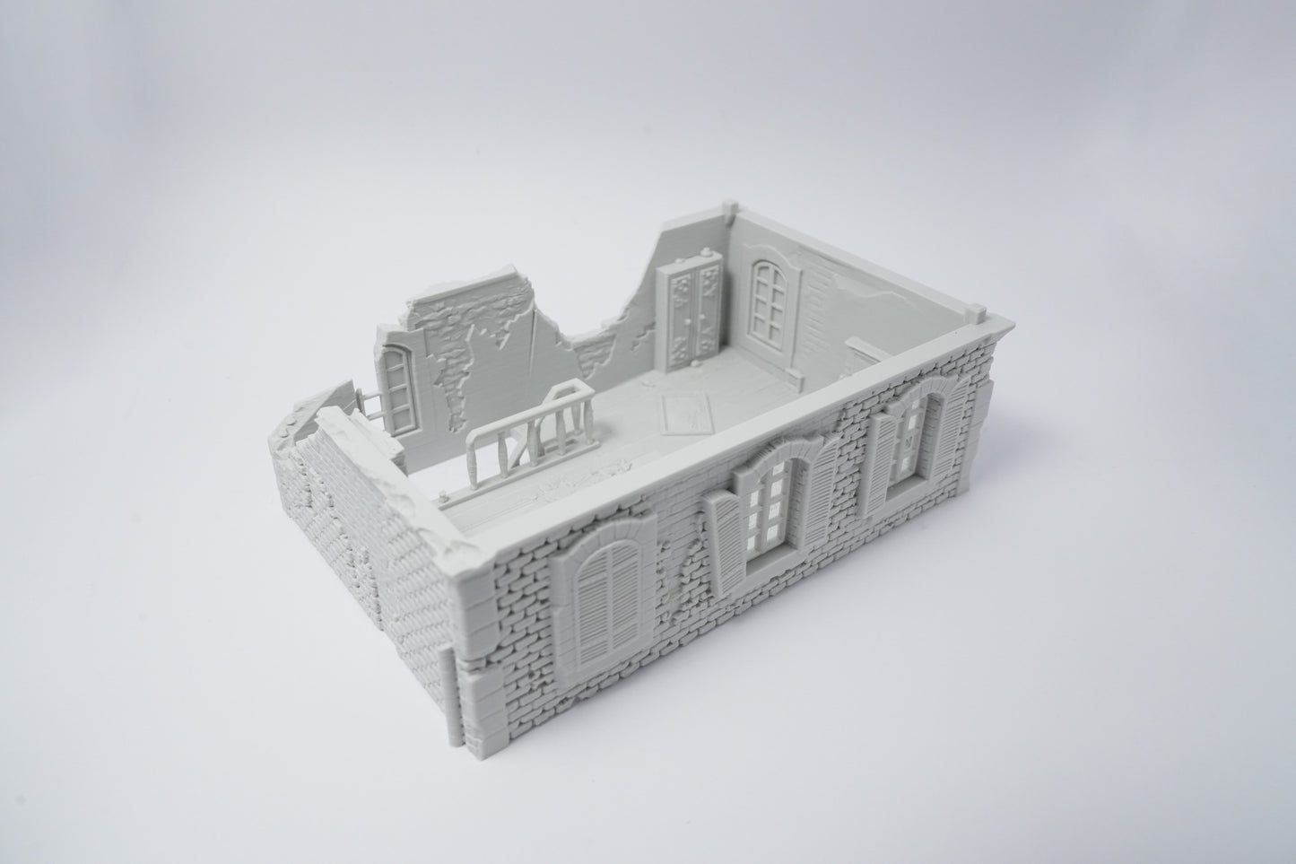 Graue Miniatur-Hausruine mit zerfallenen Mauern und Fenstern, detailreich gestaltet.