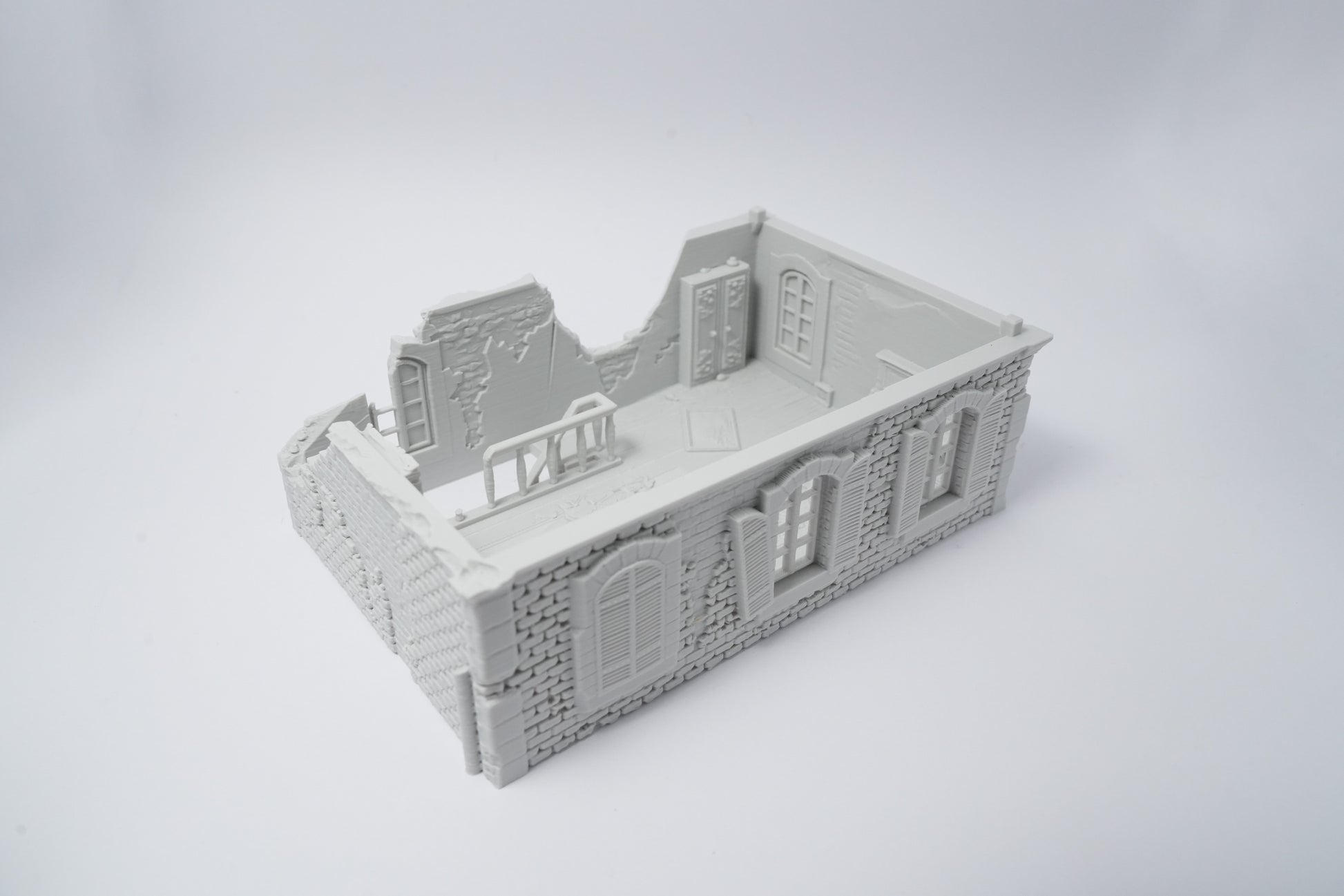 Graue Miniatur-Hausruine mit zerfallenen Mauern und Fenstern, detailreich gestaltet.