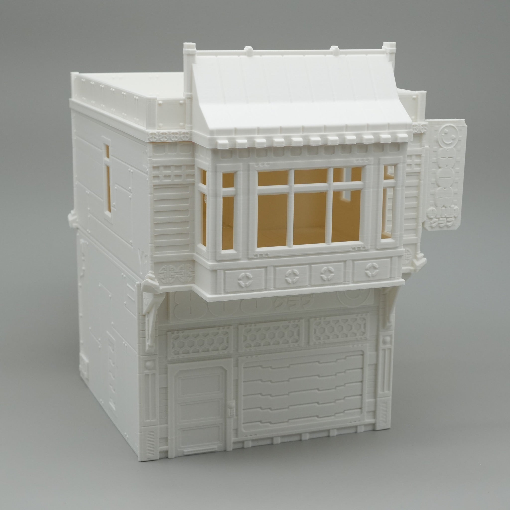 Weißes mehrstöckiges Modellhaus mit Balkonen und dekorativen Fenstern.