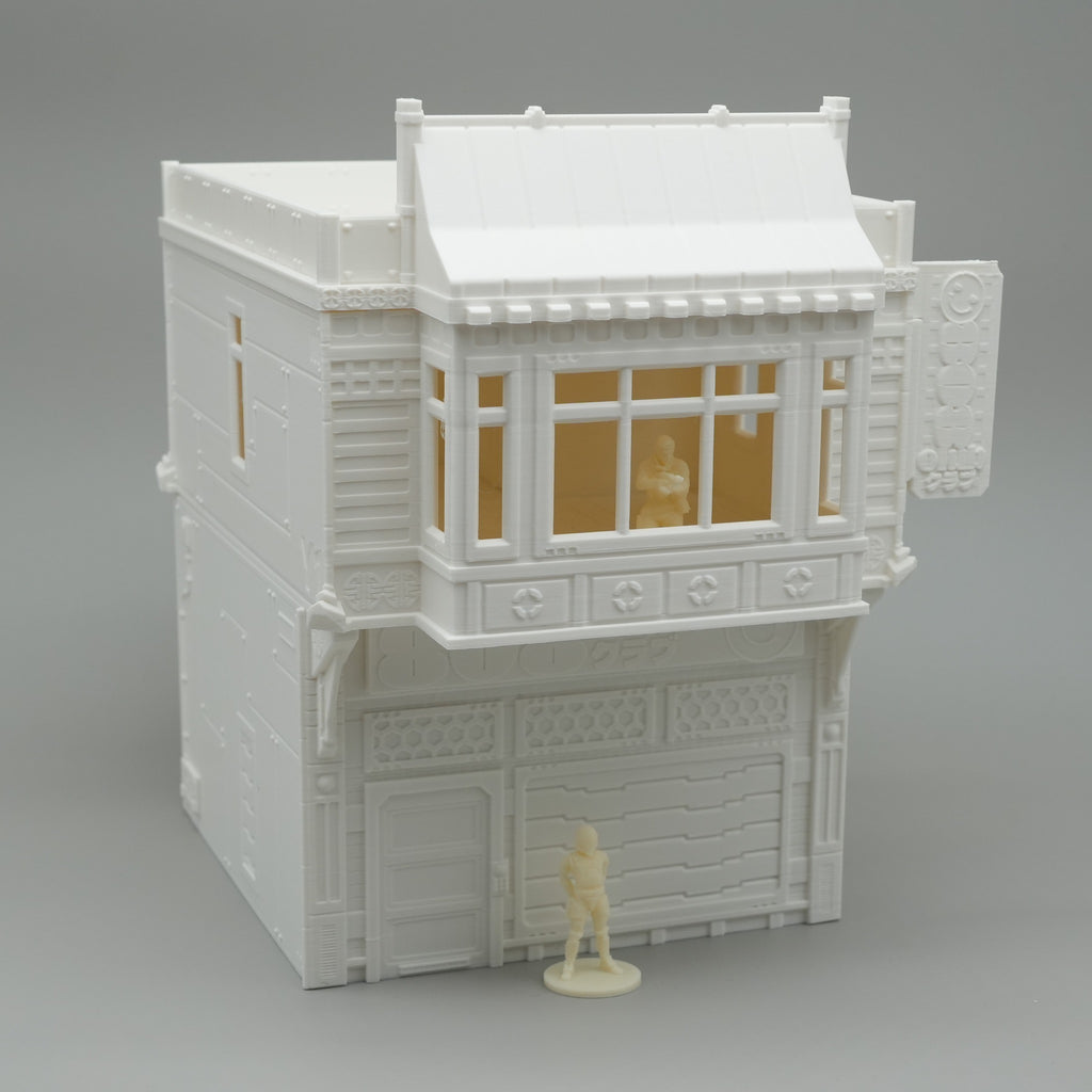 Weißes zweistöckiges Gebäude mit großen Fenstern und Wandornamenten, Miniaturfigur davor.