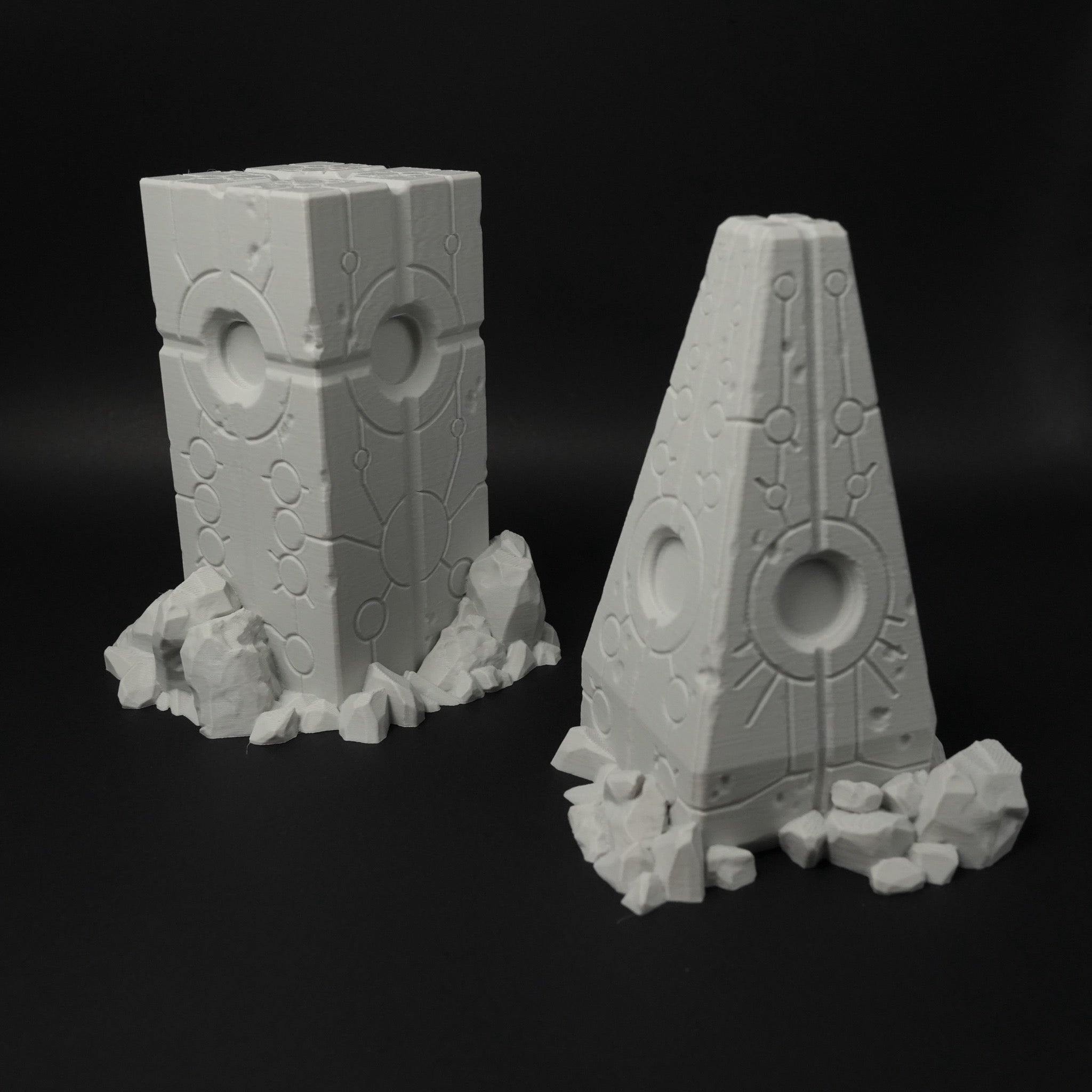 Zwei graue Alien-Obelisken mit futuristischen Mustern und zerklüftetem Sockel aus Felsen, 28mm.