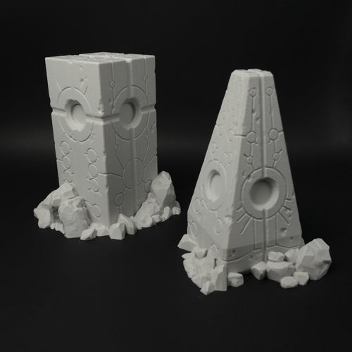 Zwei graue Alien-Obelisken mit futuristischen Mustern und zerklüftetem Sockel aus Felsen, 28mm.