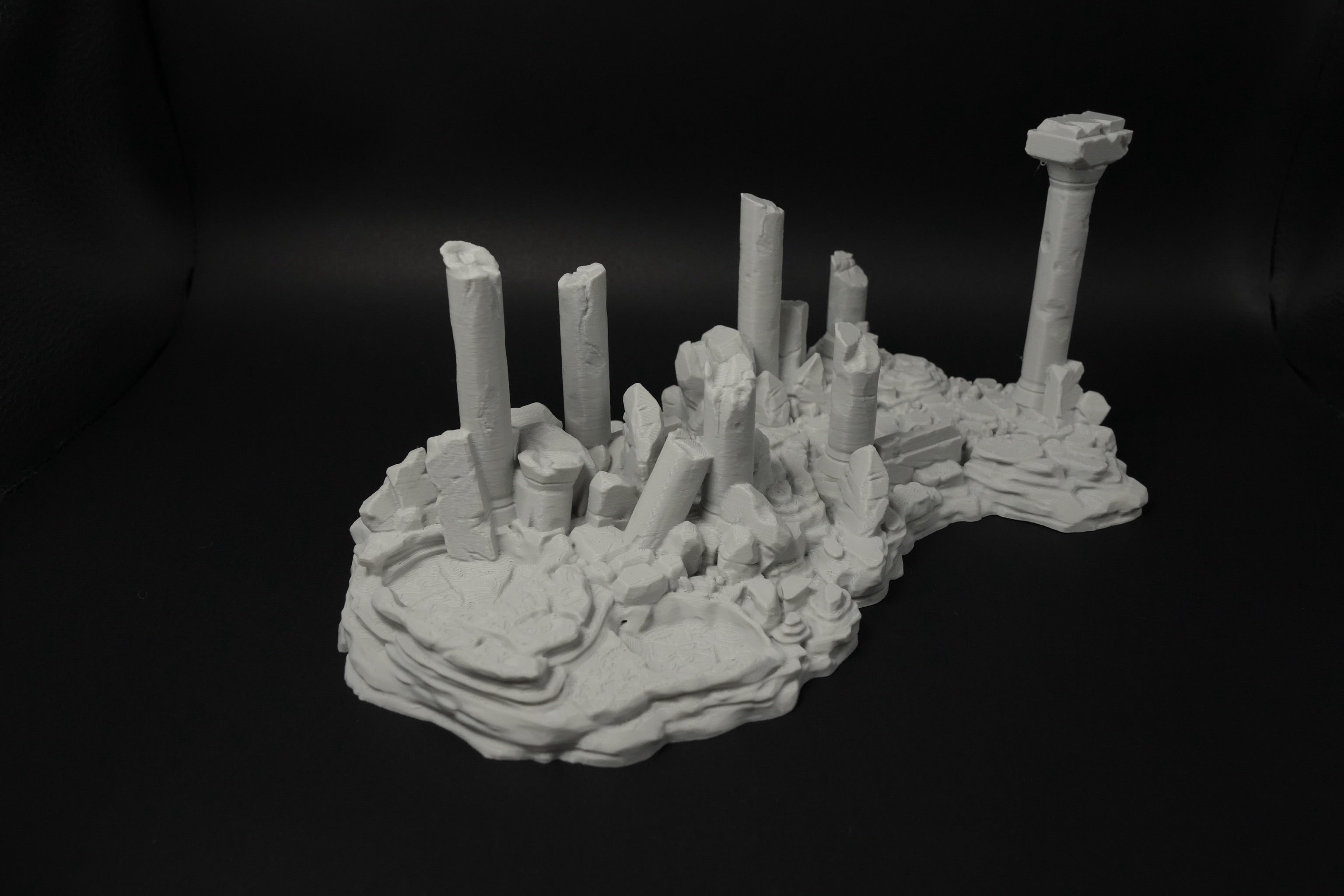 Weißes 3D-Modell verwitterter antiker Ruinen mit zerbrochenen Säulen und unebenem Gelände.