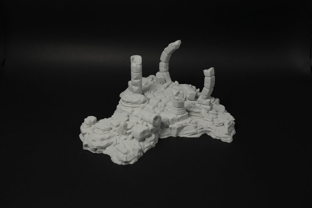 Graue Miniatur-Verwitterte Ruinen mit zerbrochenen Säulen und unebener Struktur auf schwarzem Hintergrund.