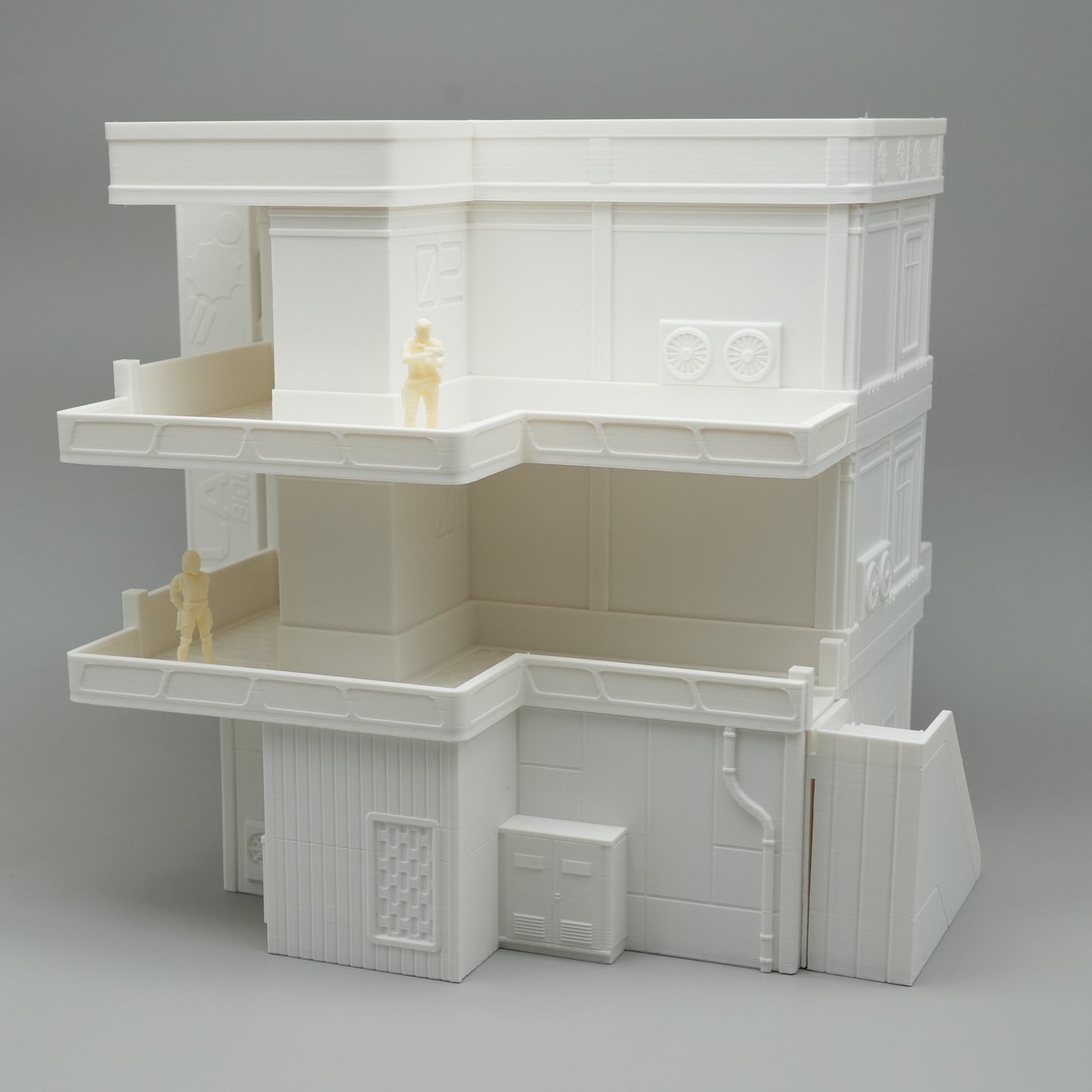 Weißes mehrstöckiges Modell eines Apartmentgebäudes mit Balkonen und kleinen Figuren.