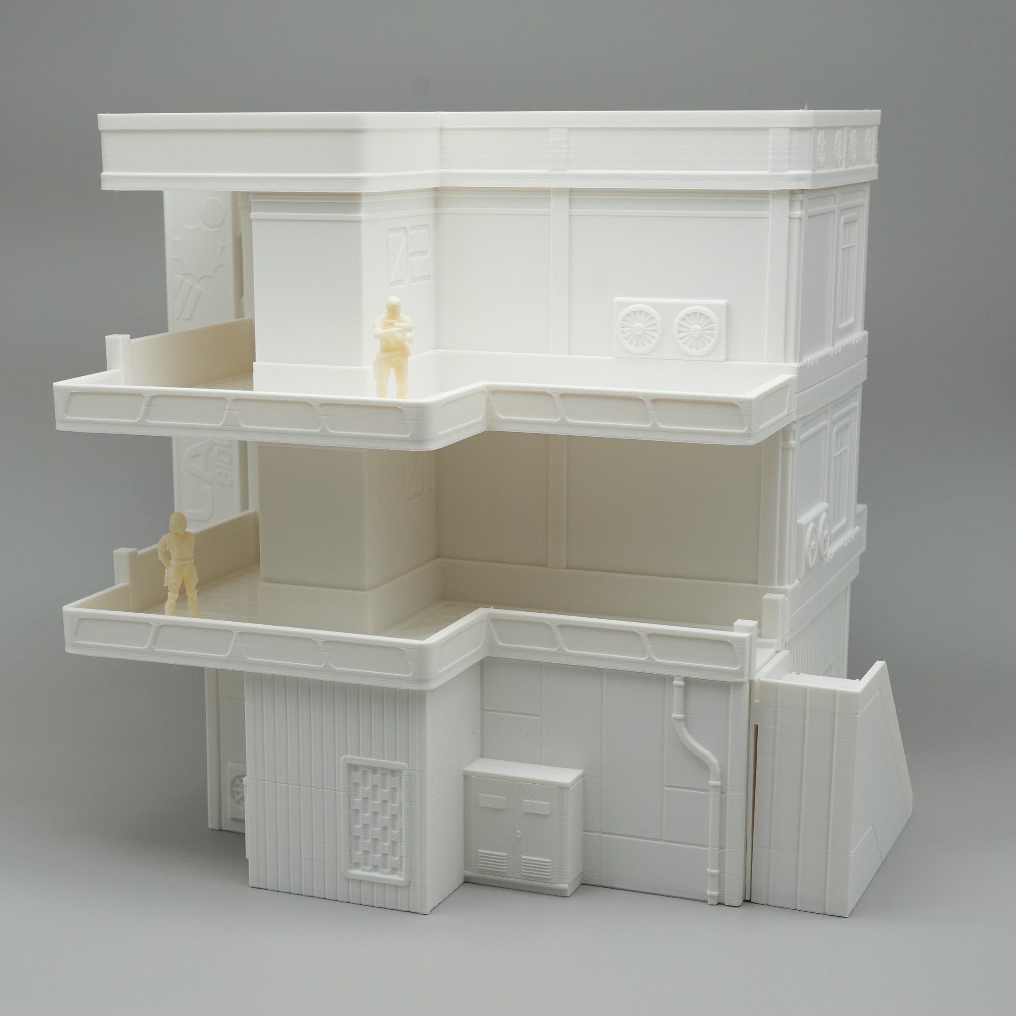 Weißes mehrstöckiges Modell eines Apartmentgebäudes mit Balkonen und kleinen Figuren.