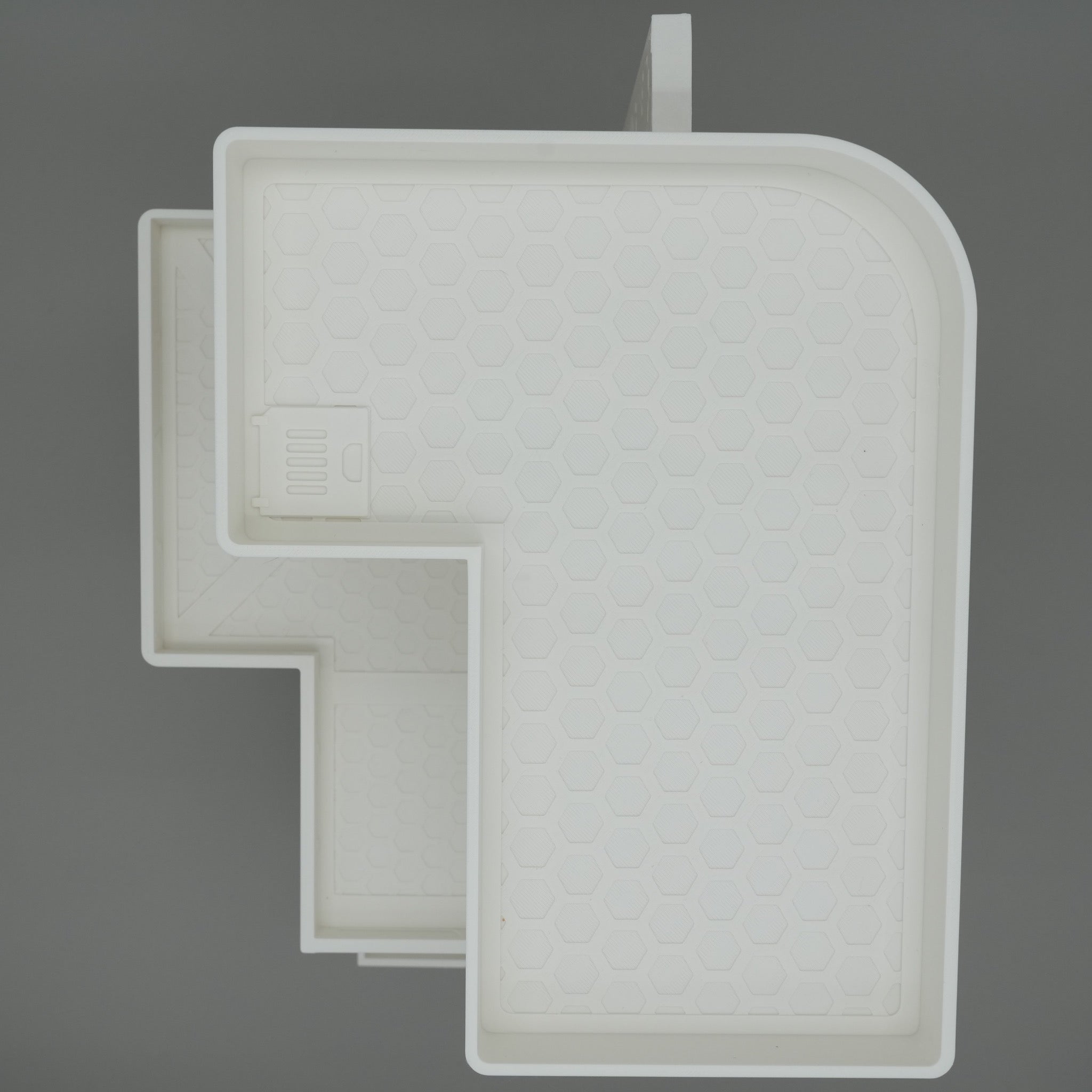 Großes hellgraues Wohngebäude mit L-förmigem Grundriss aus Kunststoff.