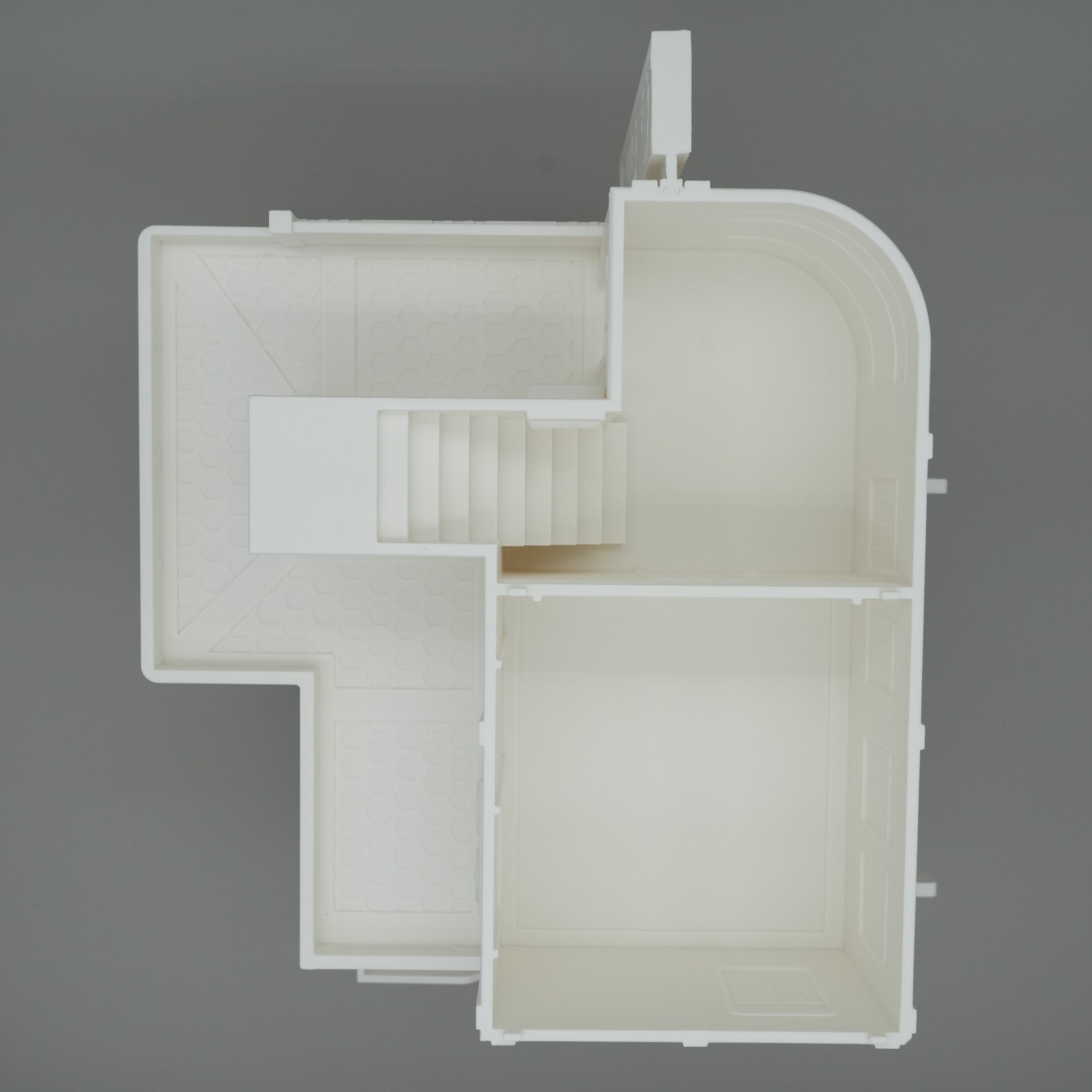 Modell eines großen, weißen Apartmentgebäudes mit Treppenhaus und klar abgegrenzten Räumen von oben betrachtet.