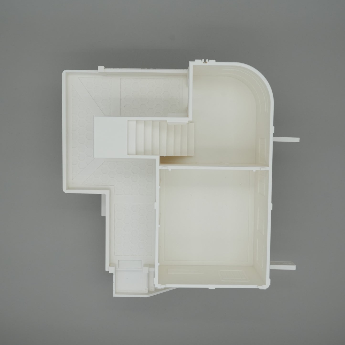 Weißes Modell eines großen Wohnhaus-Grundrisses mit Treppe, geraden und abgerundeten Wänden.