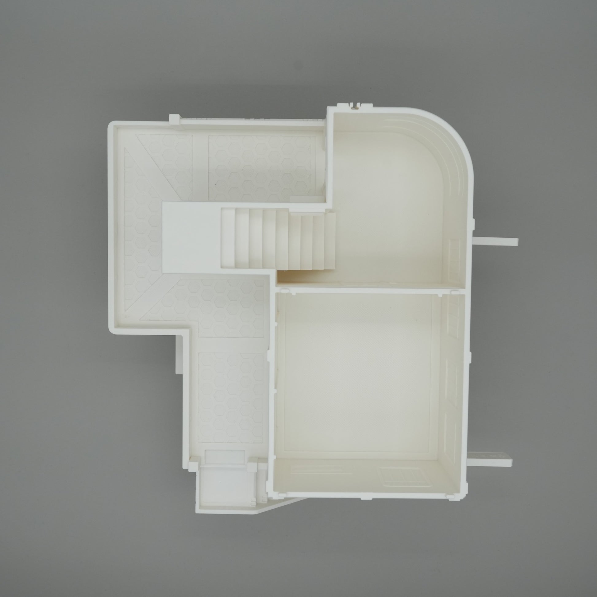 Weißes Modell eines großen Wohnhaus-Grundrisses mit Treppe, geraden und abgerundeten Wänden.