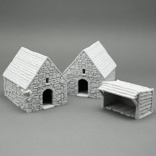 Drei kleine rustikale Modelle von Scheunen und Holzschuppen aus grauem Stein und Holz mit detaillierten Strukturen.