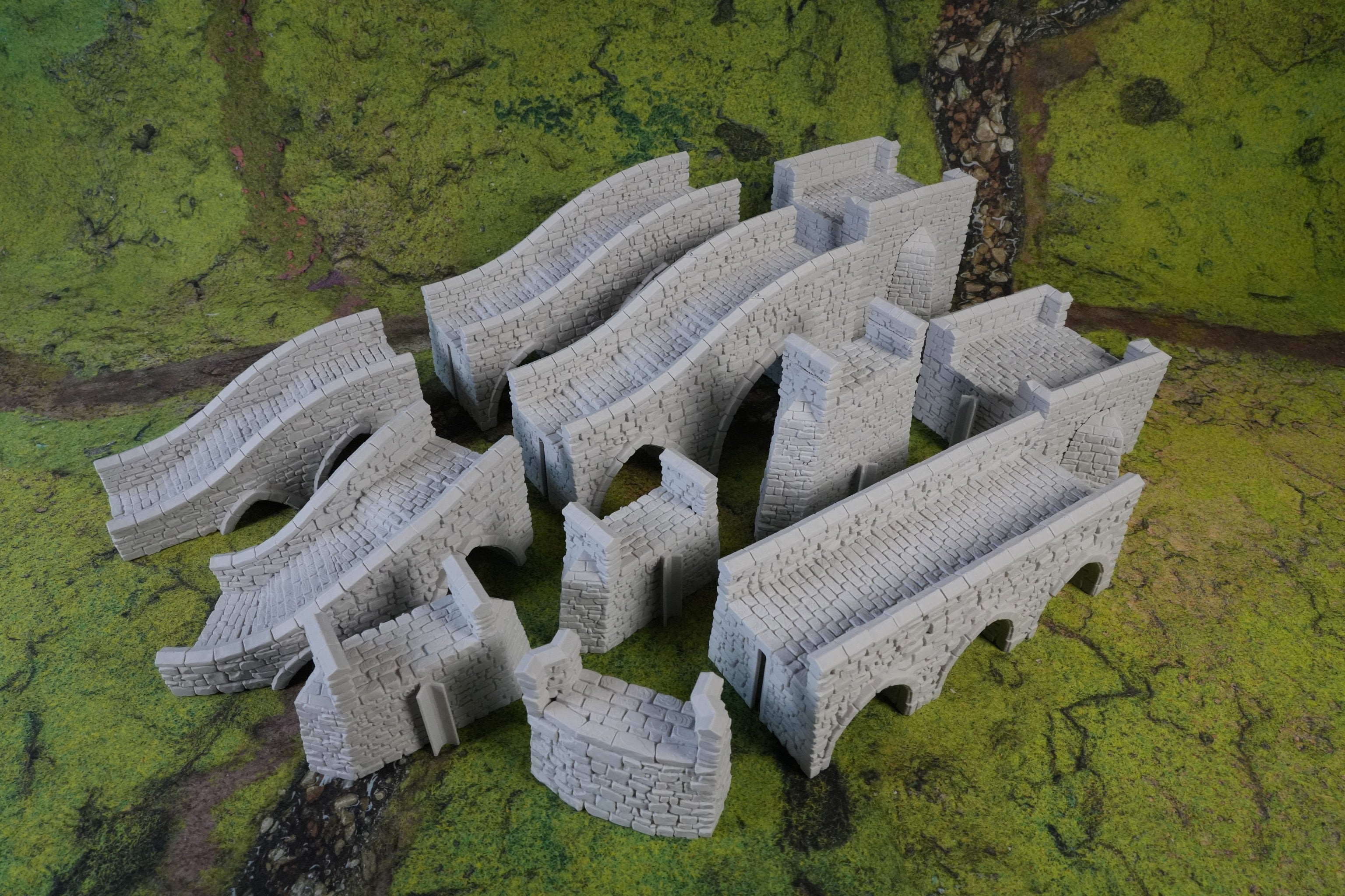 Modulare graue Steinbrückenstücke mit Bögen in verschiedenen Größen auf grünem Untergrund.
