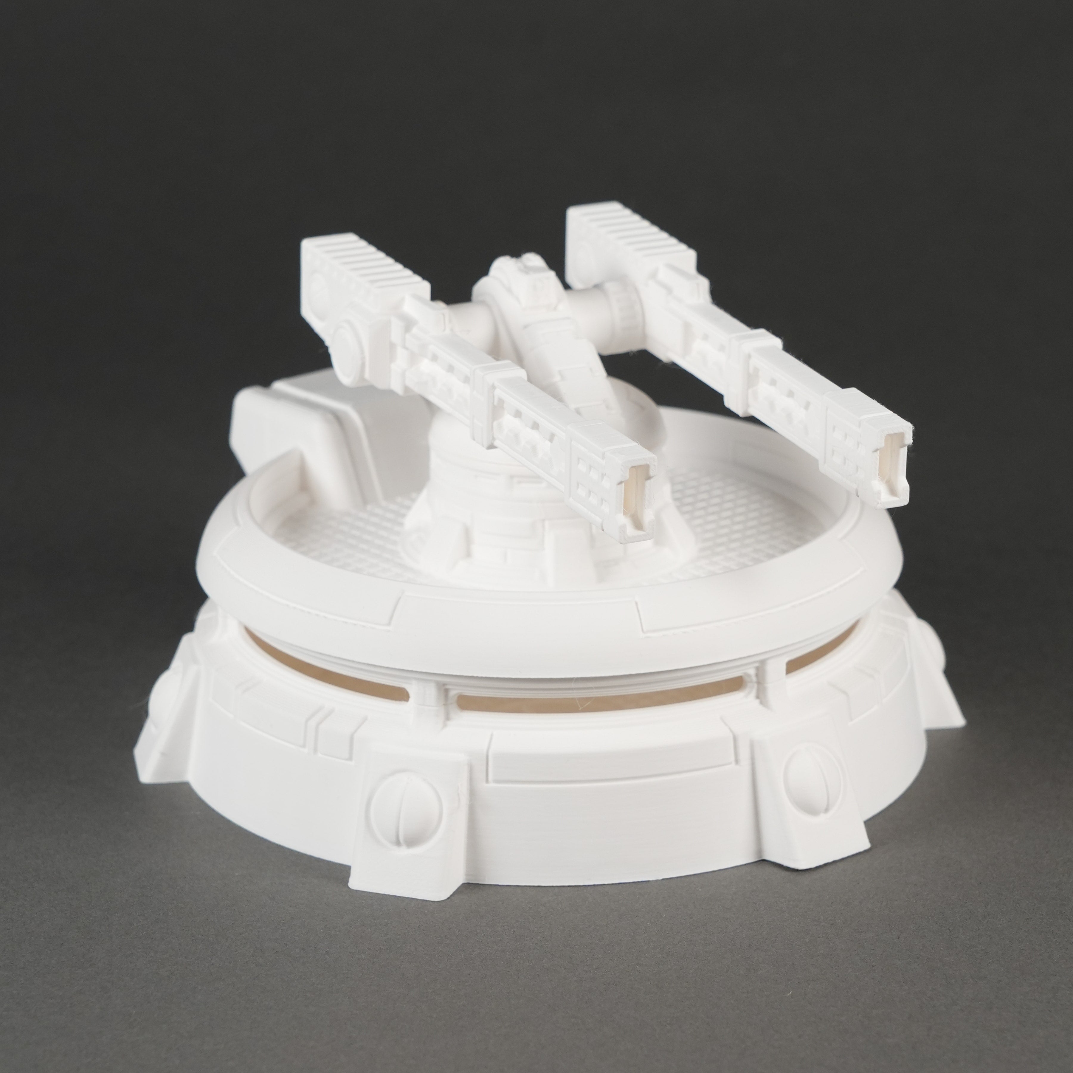 Weißer Miniatur-Bunker mit drehbarer Kanone auf rundem Sockel, detailreich gestaltet.