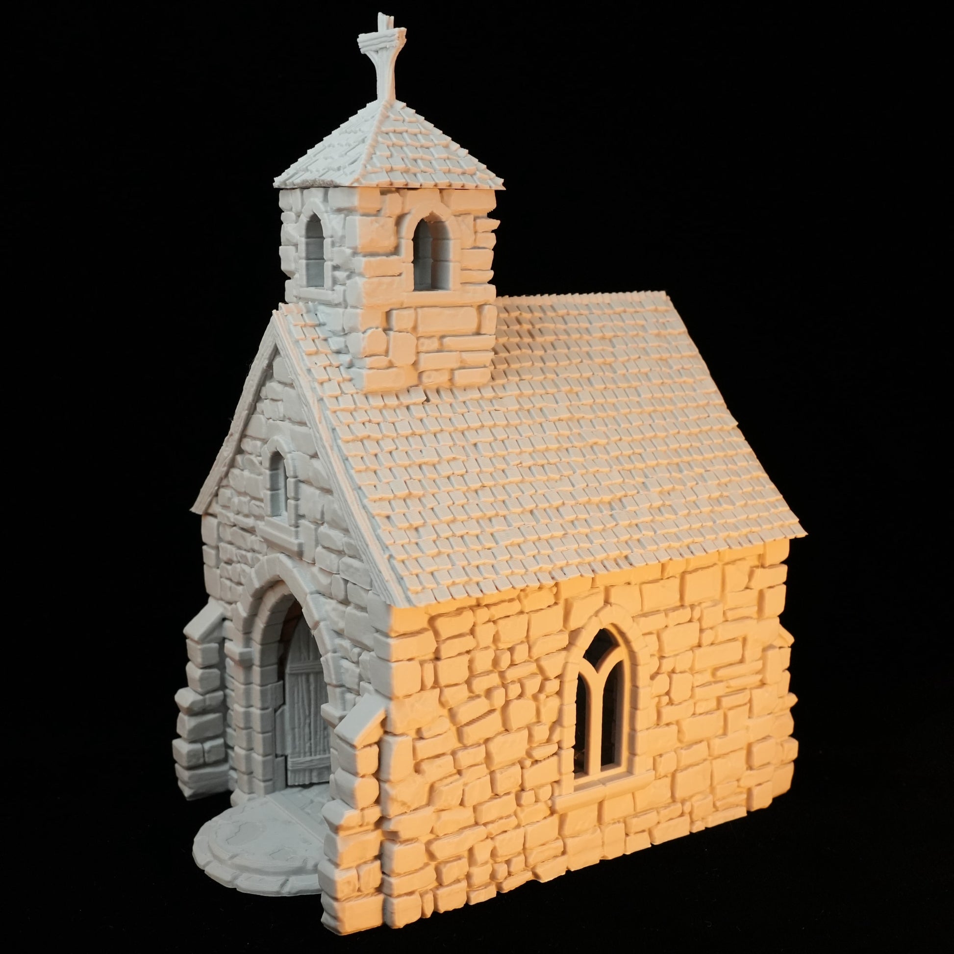 Kleine steinerne Kapelle mit Spitzdach und Kreuz auf Glockenturm.