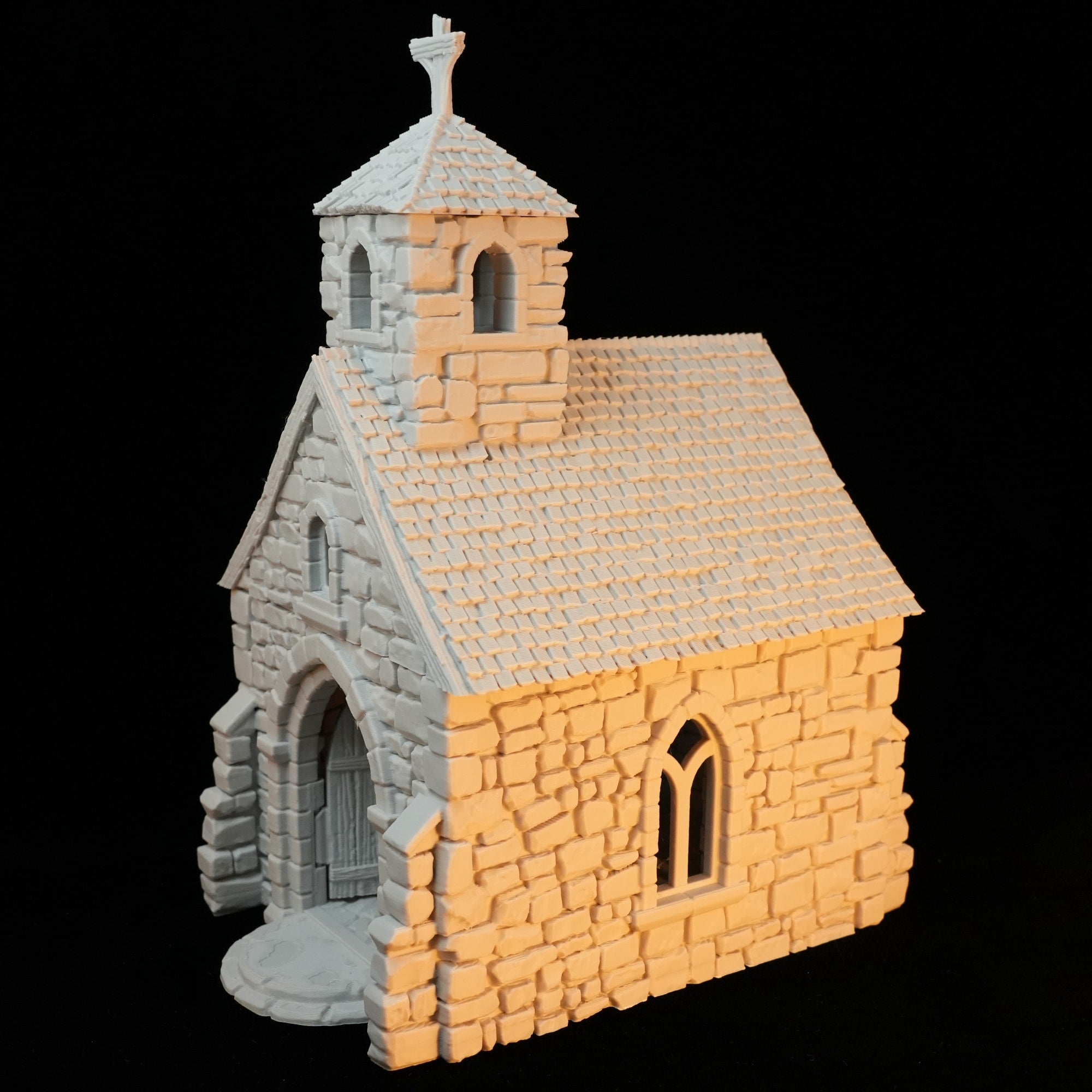 Kleine steinerne Kapelle mit Spitzdach und Kreuz auf Glockenturm.