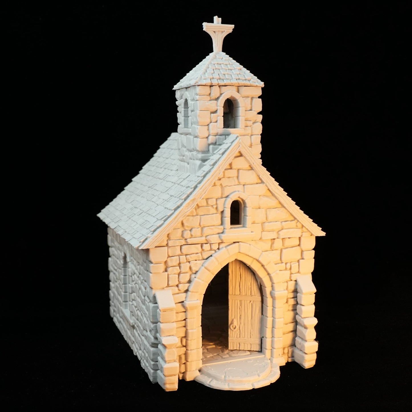 Kleine Kapelle aus Stein mit Spitzdach, Rundbogenportal und Glockenturm mit Kreuz.