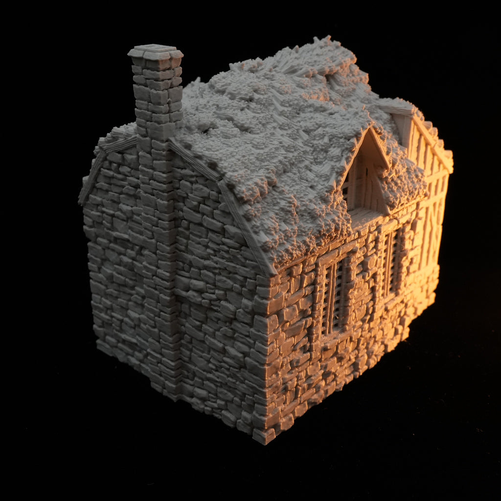 Rustikales Bauernhaus aus Stein mit hohem Schornstein und detailreichem Dach in Grau.