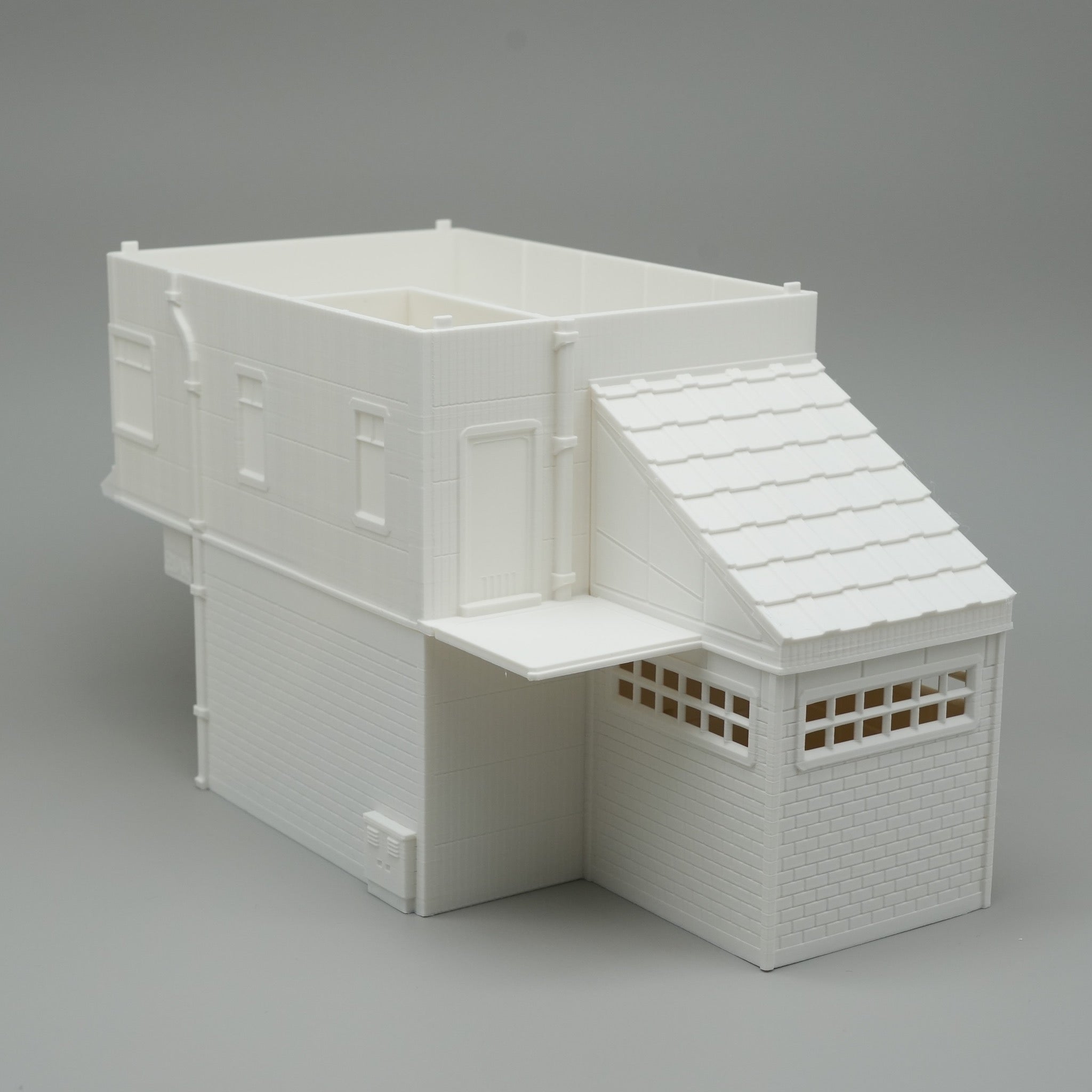 Weißes, modernes zweistöckiges Modellgebäude mit Flachdach und schrägem Anbau.