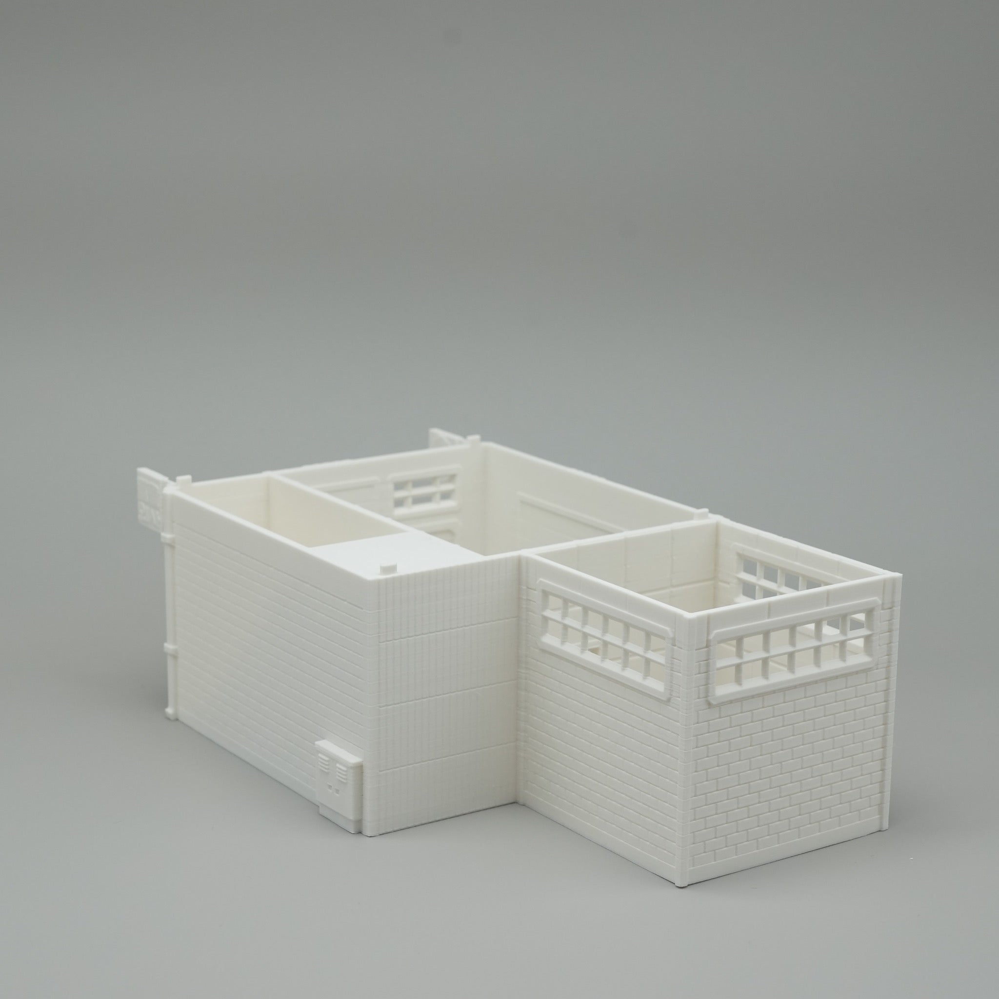 Weißes, modernes Modellgebäude mit rechteckigem Grundriss und Fensterdetails.