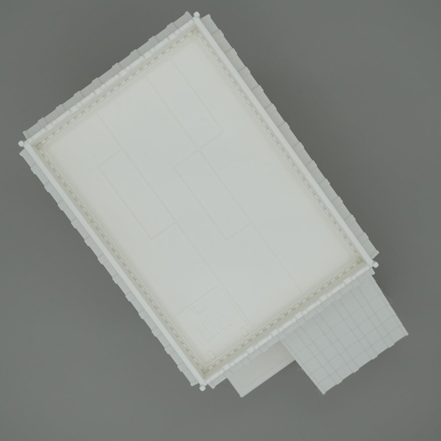Weißes rechteckiges Gebäude mit Flachdach und vorgelagertem Eingang, klare Linien, modernes Design.