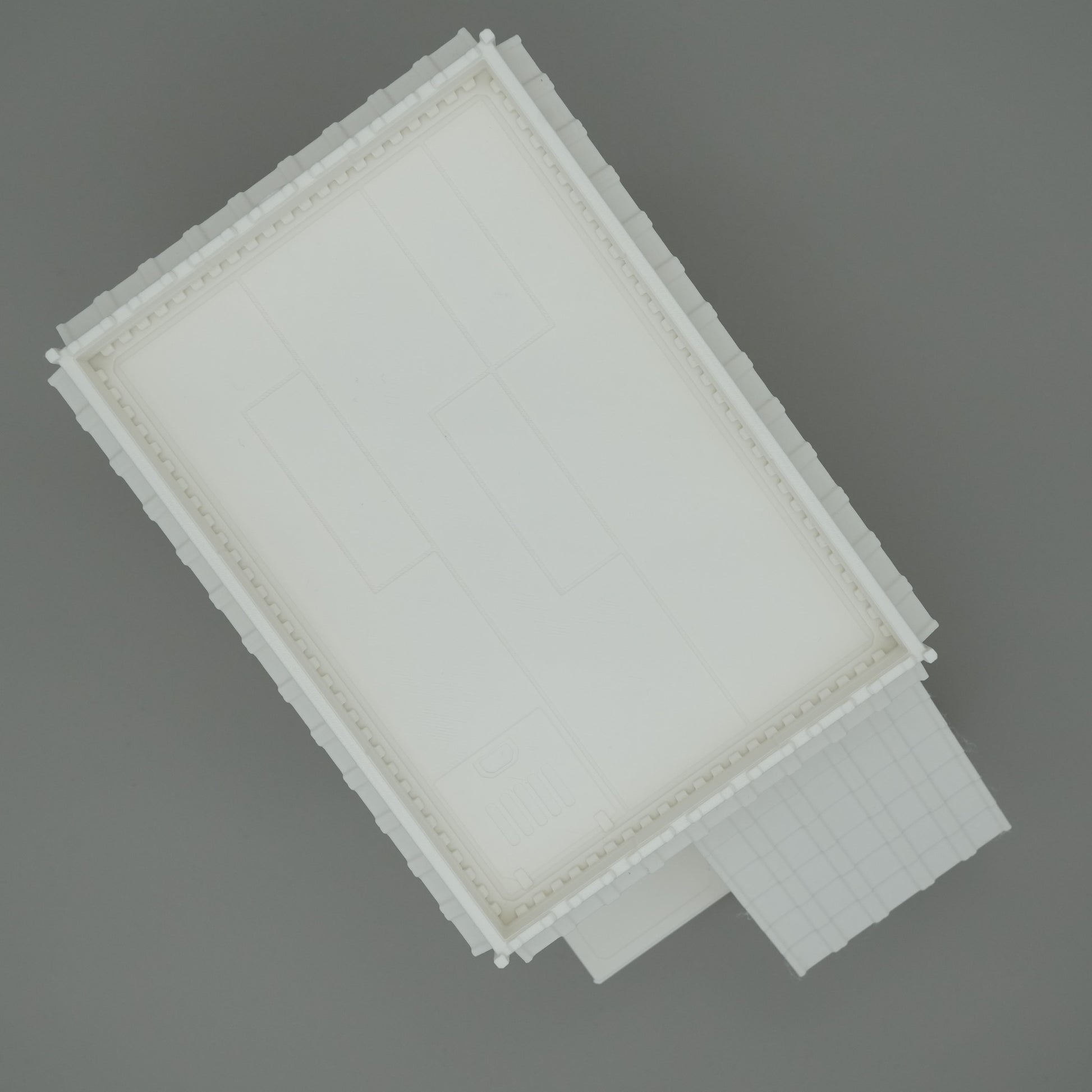 Weißes rechteckiges Gebäude mit Flachdach und vorgelagertem Eingang, klare Linien, modernes Design.