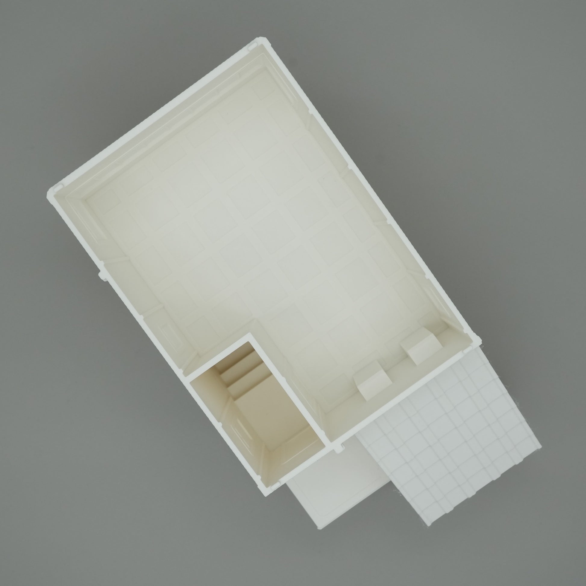 Weißes, minimalistisch-modernes Gebäude mit kleinem Eingangsbereich und Treppen, Draufsicht.