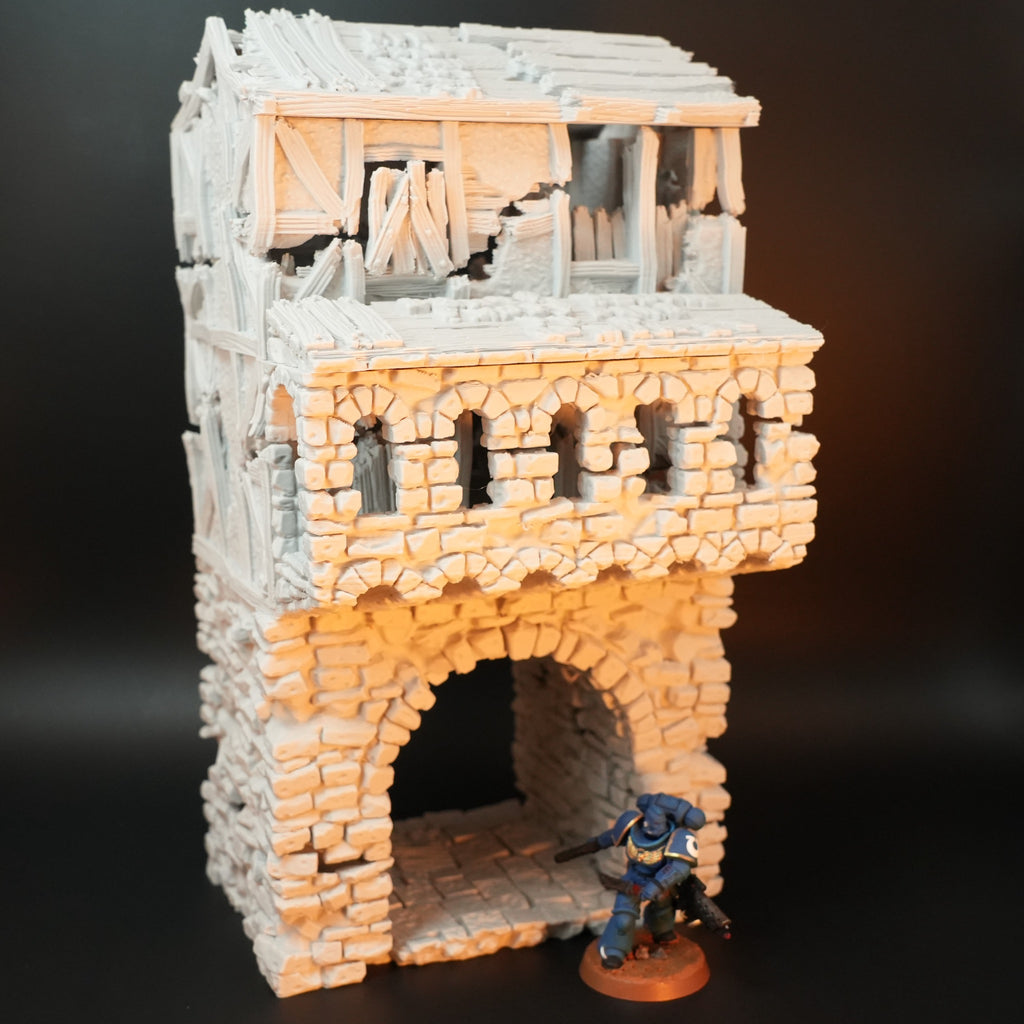 Verwittertes Torhaus aus Stein mit großem Bogen und verwittertem Fachwerkdach, Miniaturfigur im Vordergrund.