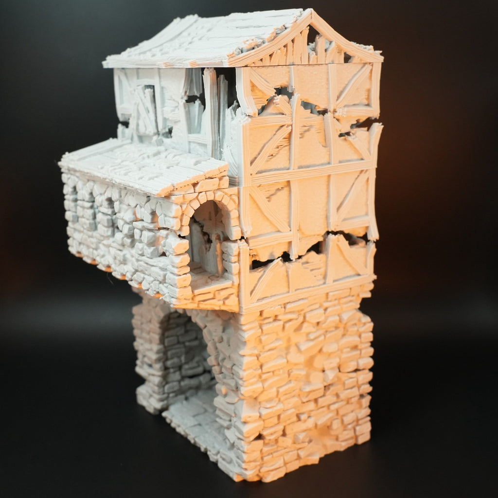 Zweistöckiges Torhaus mit verwittertem Steinsockel und hölzerner Fachwerkfassade, Tor mit Rissen und zerbrochenen Teilen.