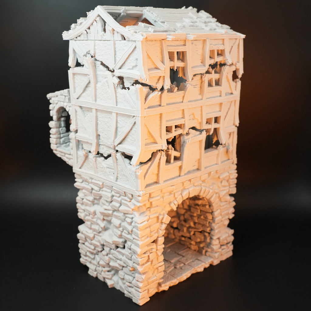 Zweistöckiges, verwittertes Torhaus mit Steinmauerwerk, gebrochenen Holzbalken und großen Torbogen.