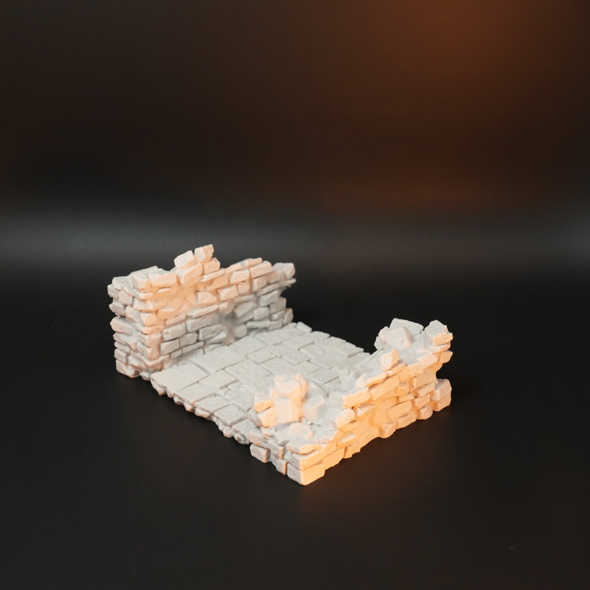 Helle, verwitterte Steinmauer mit Torhausfragment und gepflastertem Boden aus unregelmäßigen Steinen.