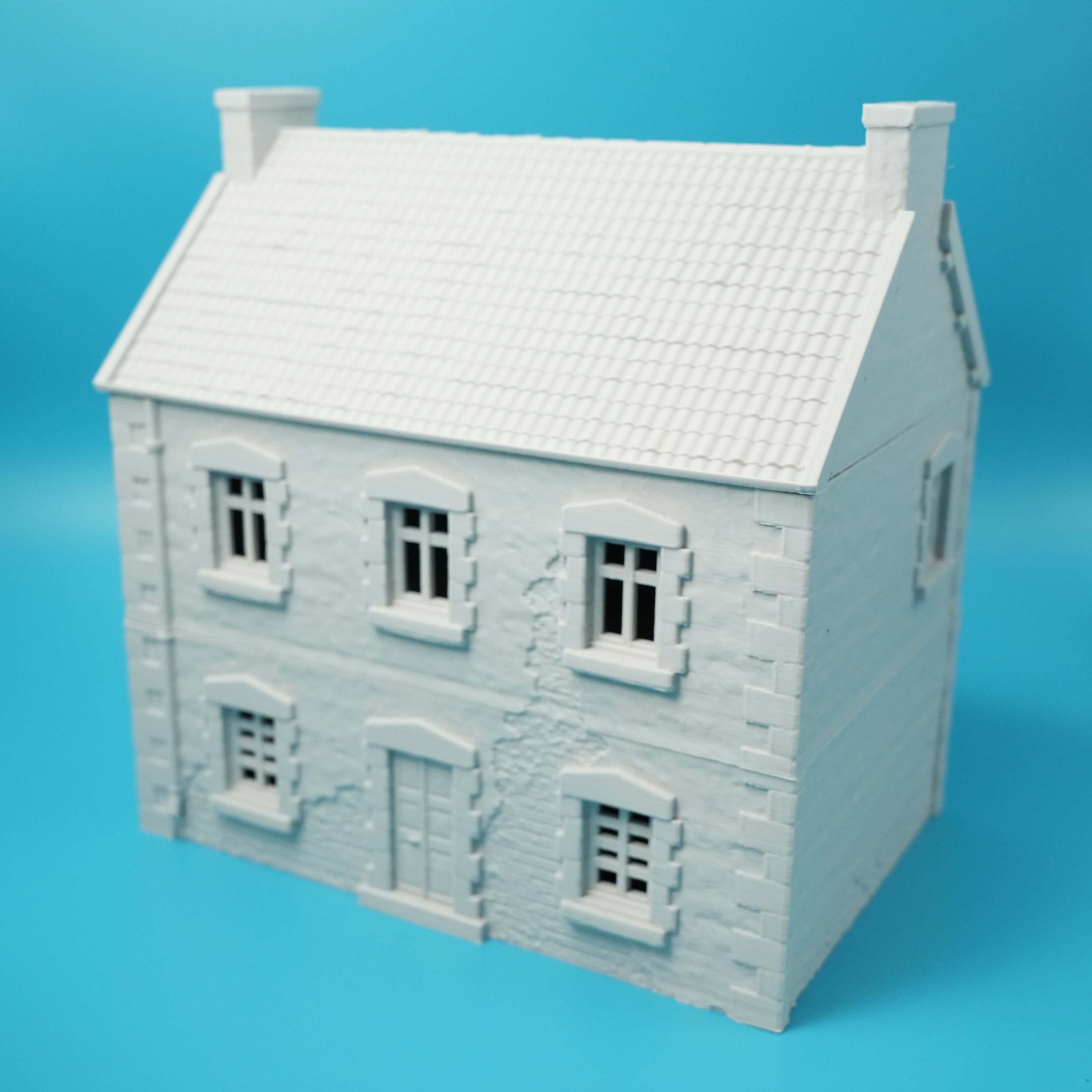 Weißes Modell eines französischen Stadthauses mit Satteldach und symmetrischen Fenstern.