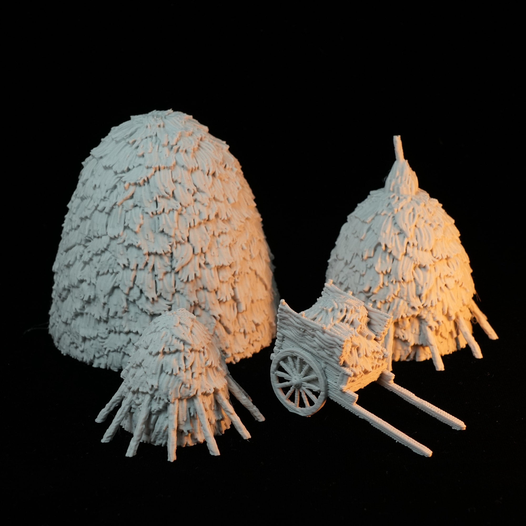 Detailliertes Miniatur-Heuhaufen- und Heuwagen-Set in naturfarbener Struktur auf schwarzem Hintergrund.