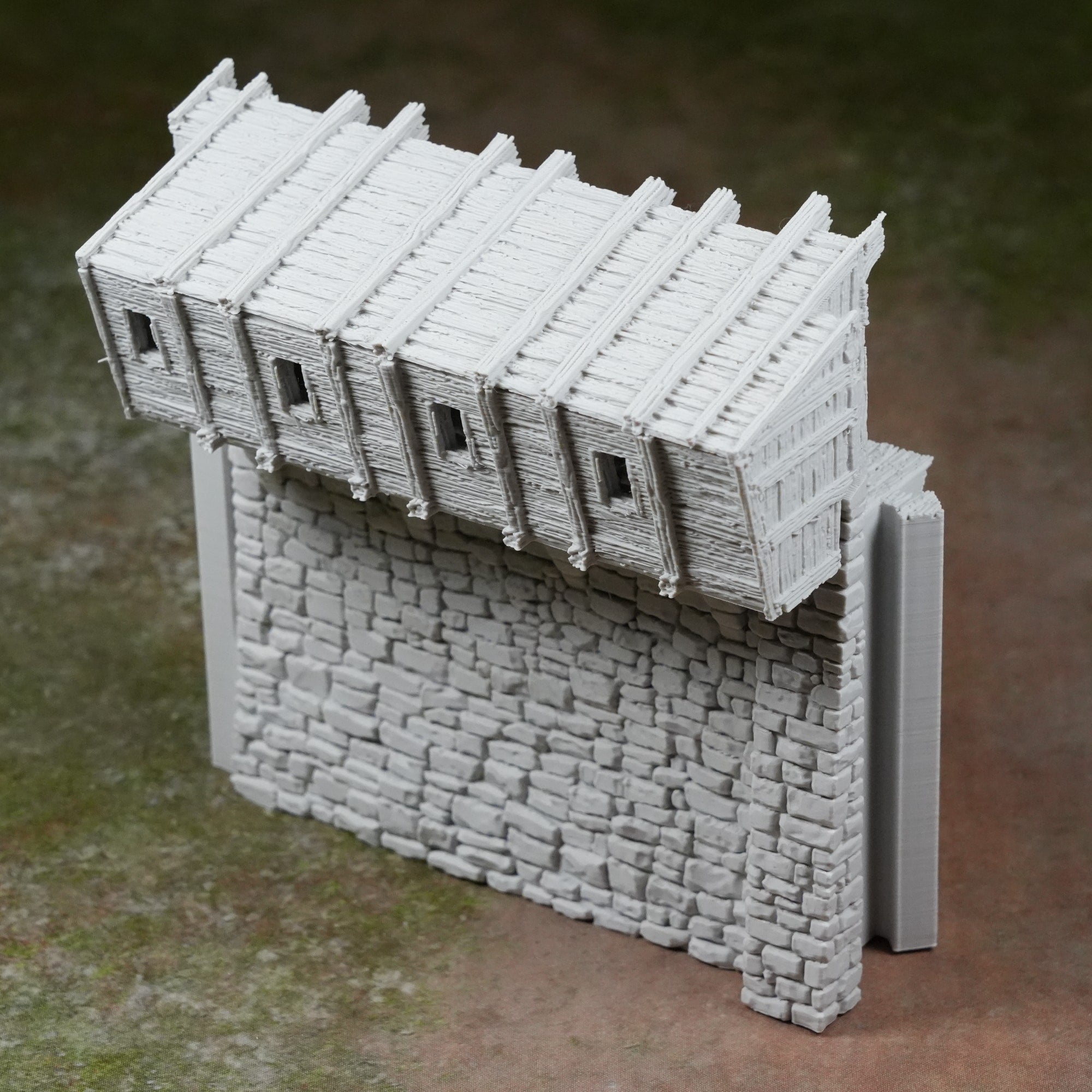 Grauer Maueraufsatz mit Zinnen im mittelalterlichen Festungsstil aus Kunststoff, detailreiche Steinstruktur.