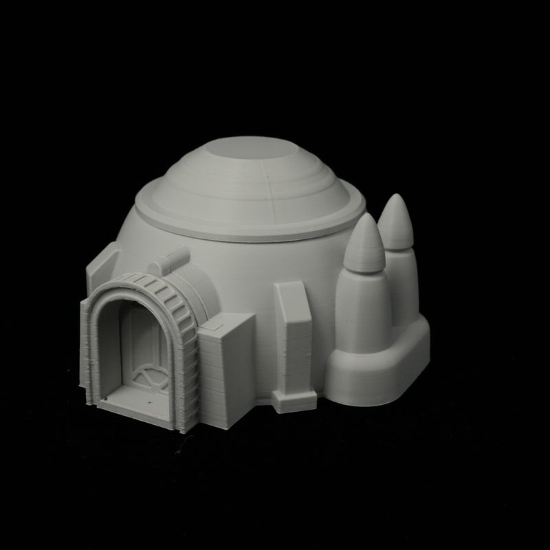 Graues 3D-gedrucktes Wüstenhaus mit rundem Kuppeldach und zwei Turmspitzen auf schwarzem Hintergrund.