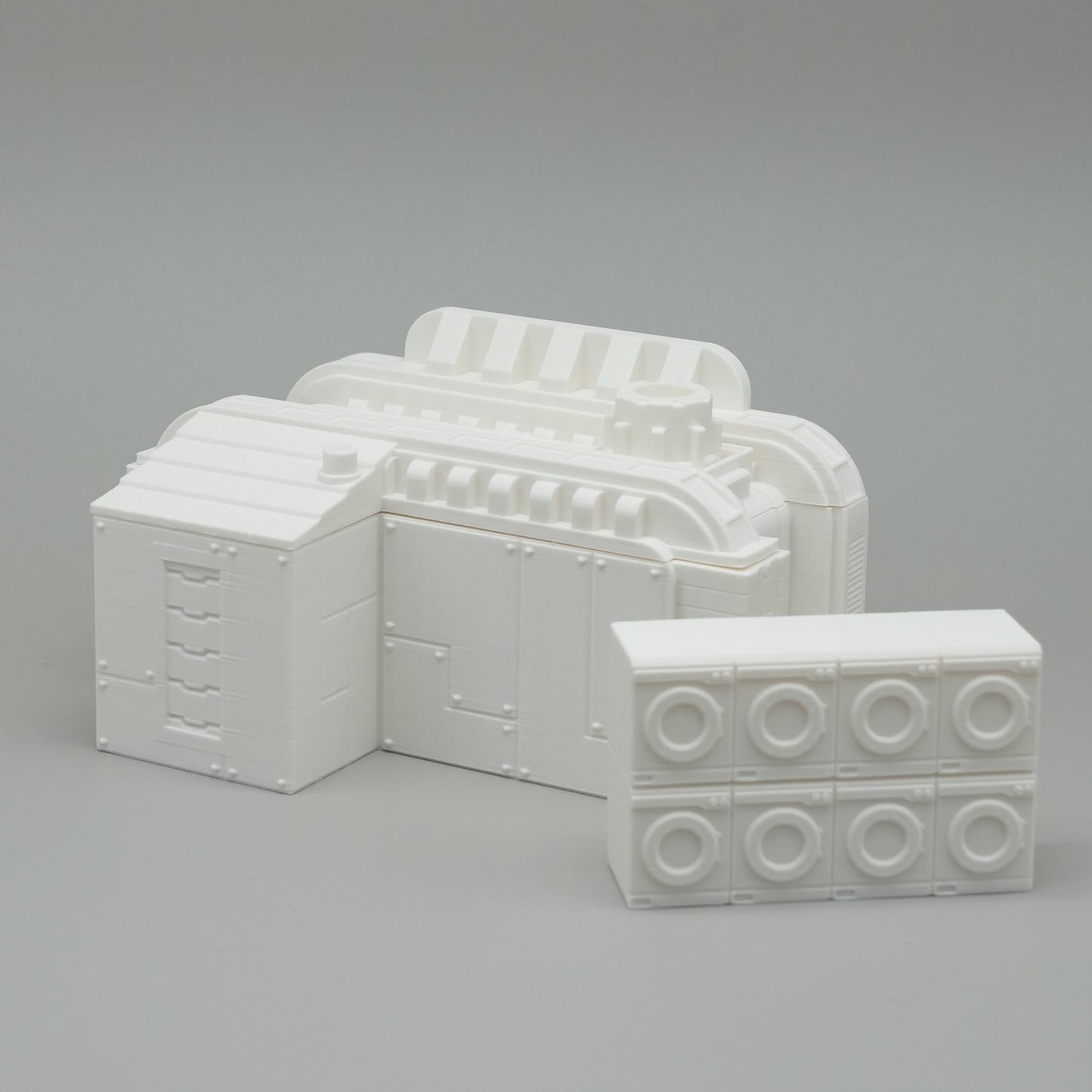 Weißes architektonisches Modell mit strukturierten und glatten Blockelementen auf grauem Hintergrund.
