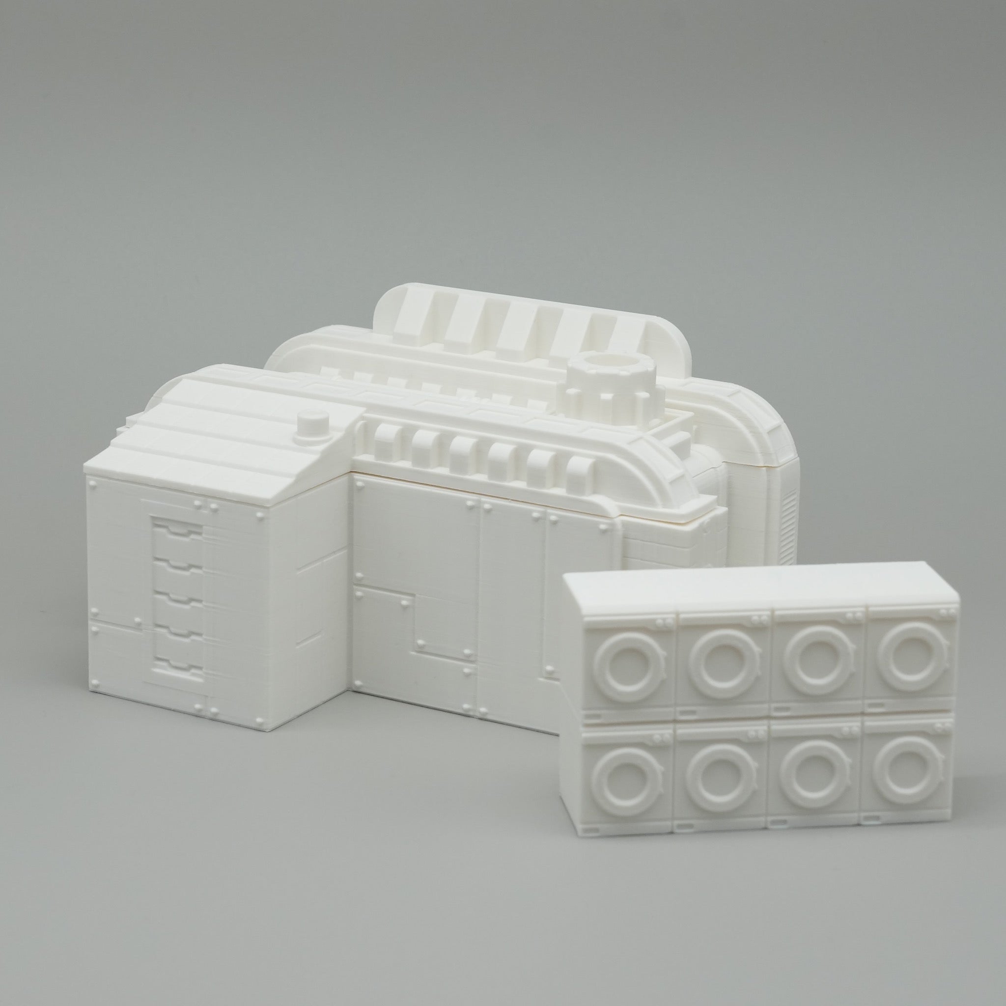 Weißes architektonisches Modell mit strukturierten und glatten Blockelementen auf grauem Hintergrund.