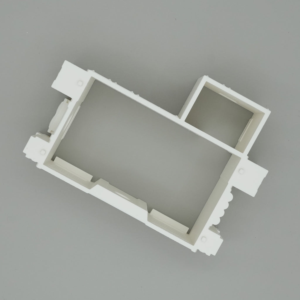 Weißes, rechteckiges Miniatur-Hausmodell mit minimalistischer Raumaufteilung auf grauem Hintergrund.