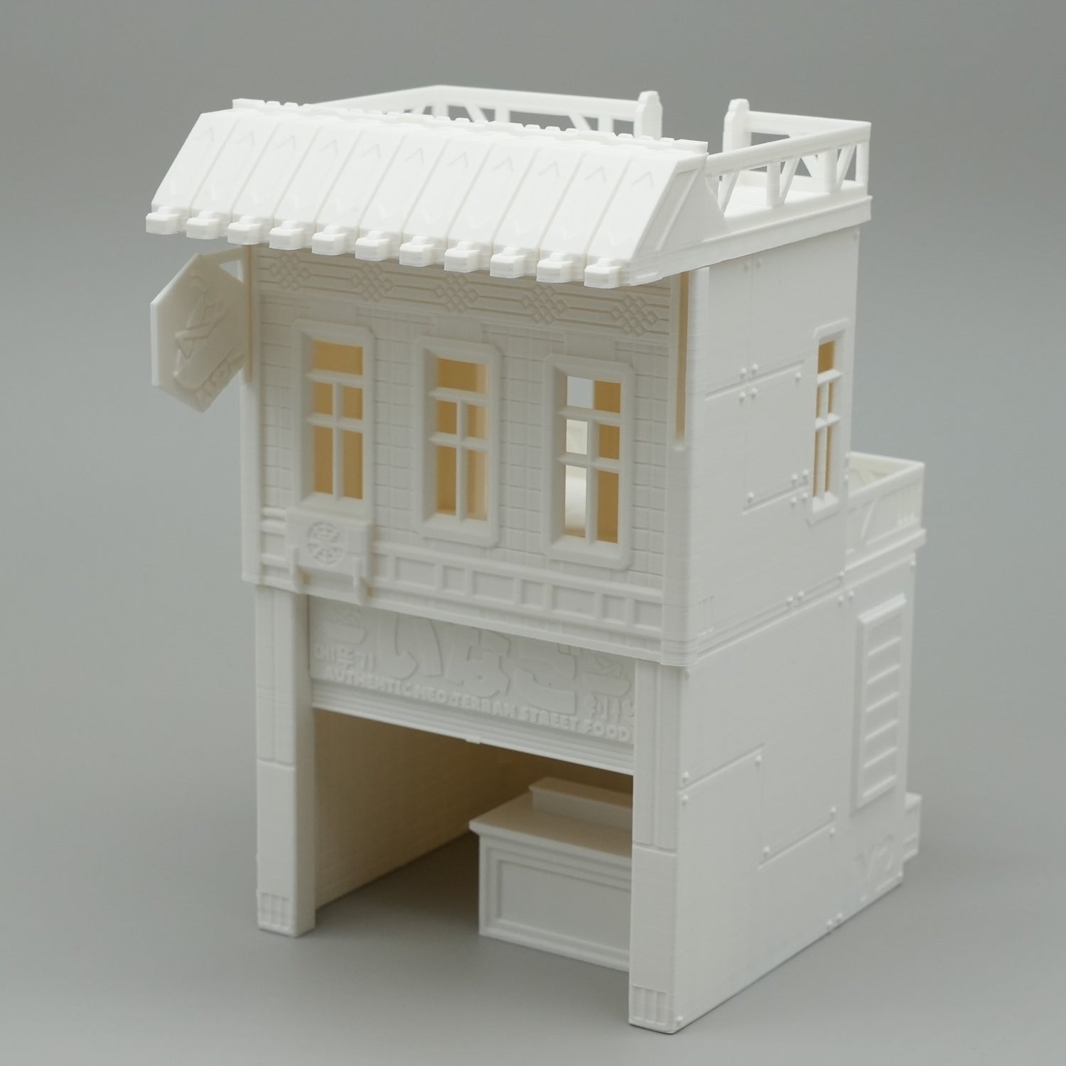 Weißes Modell eines zweistöckigen japanischen Hauses mit offenem Erdgeschoss und filigranen Fensterdetails.